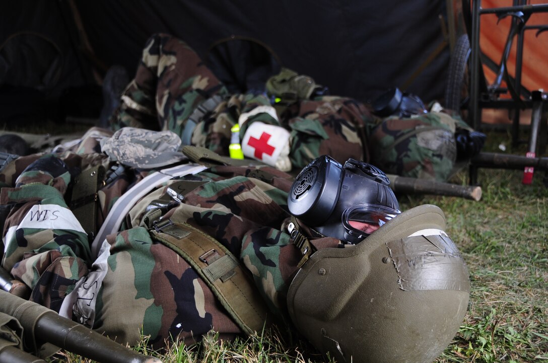 ELLSWORTH AIR FORCE BASE, S.D. -- (Back to front) Airmen 1st Class Julie Kemps, 28th Medical Operations Squadron flight medicine technician, and John Henry, 28 MDOS ambulance services technician, take cover in a simulated bunker while wearing mission-oriented protective posture gear during a phase II operational readiness exercise, July 21.  The MOPP gear is designed to protect Airmen in case of a chemical or biological-based attack. (U.S. Air Force photo/Airman 1st Class Anthony Sanchelli)
