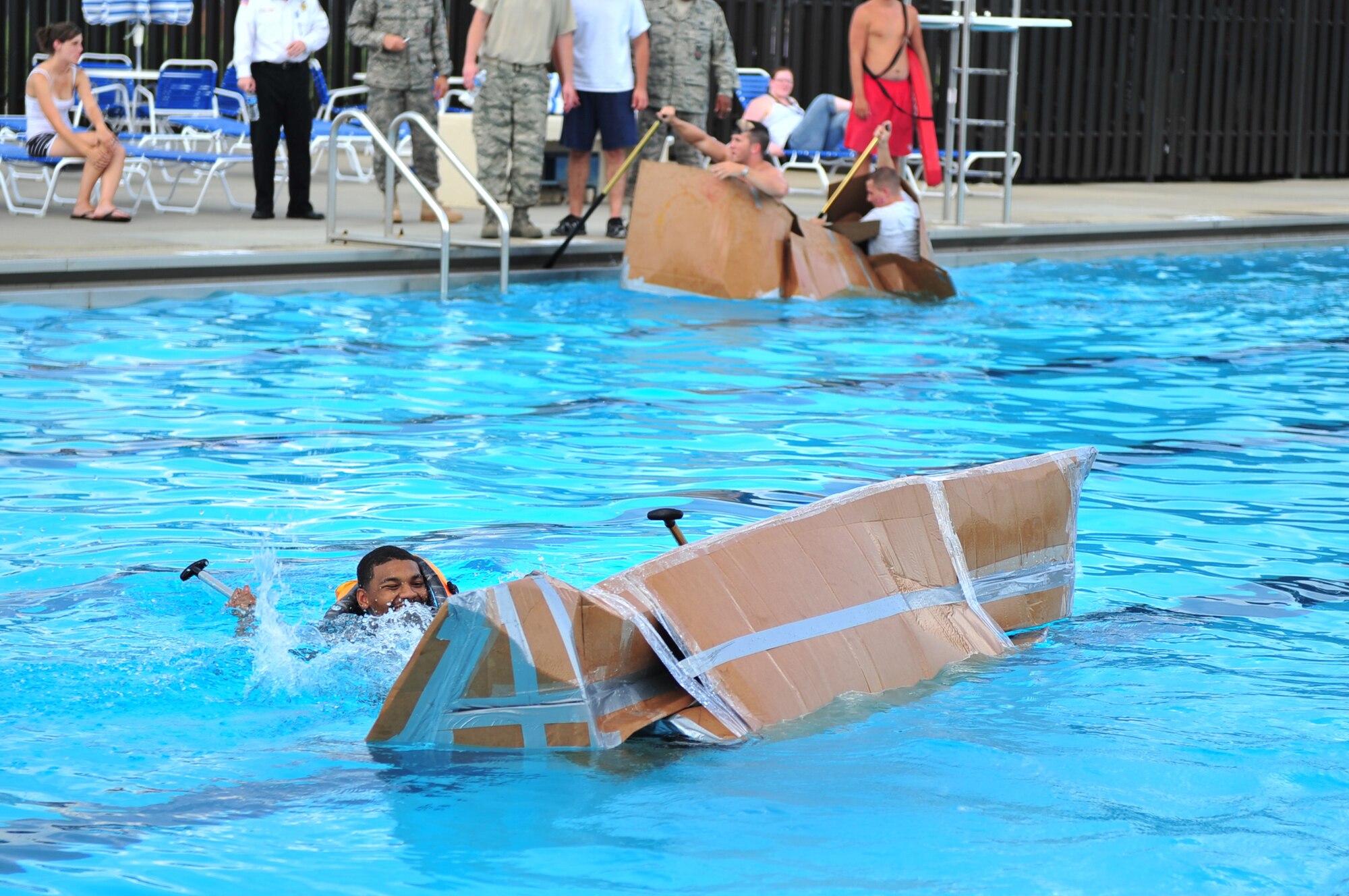 SEYMOUR JOHNSON AIR FORCE BASE, N.C. -- Airman 1st Class Rico Jackson swims beside his team's capsized boat during a Build-A-Boat competition here, July 21, 2010. In the background the 4th Civil Engineer Squadron team struggles to row their boat as it slowly takes on water. Although ten boats entered the race, only five made it to the finishline without sinking. Airman Jackson is a member of the 4th Component Maintenance Squadron Modular Repair team two. Airman Jackson hails from Dallas. (U.S. Air Force photo/Senior Airman Rae Perry)