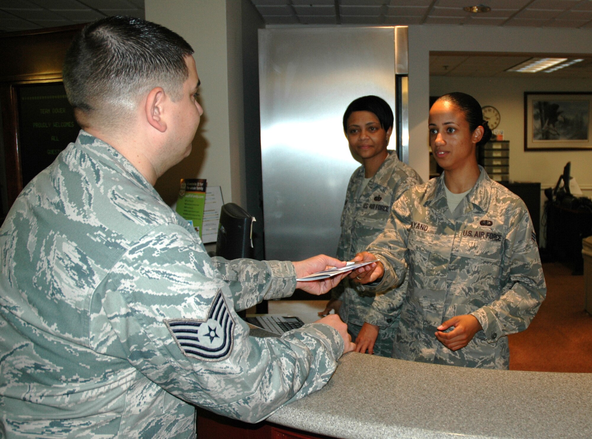 Tech. Sgt. Tracey Taylor, (middle), 512th Memorial Affairs Squadron, lodging supervisor, oversees Senior Airman Lisibeth Payano, (right), 512th MAS, lodging specialist, as she checks a guest into their room at the base lodging office during the unit training assembly weekend July 10. Reservists assigned to the 512th MAS have the unique mission of supporting the installation's dining facility, fitness center and lodging facilities, while providing the Air Force Mortuary Affairs Operations Center here with Air Force Reserve Command's biggest Port Mortuary support team. (U.S. Air Force photo/Master Sgt. Jake Chappelle)
