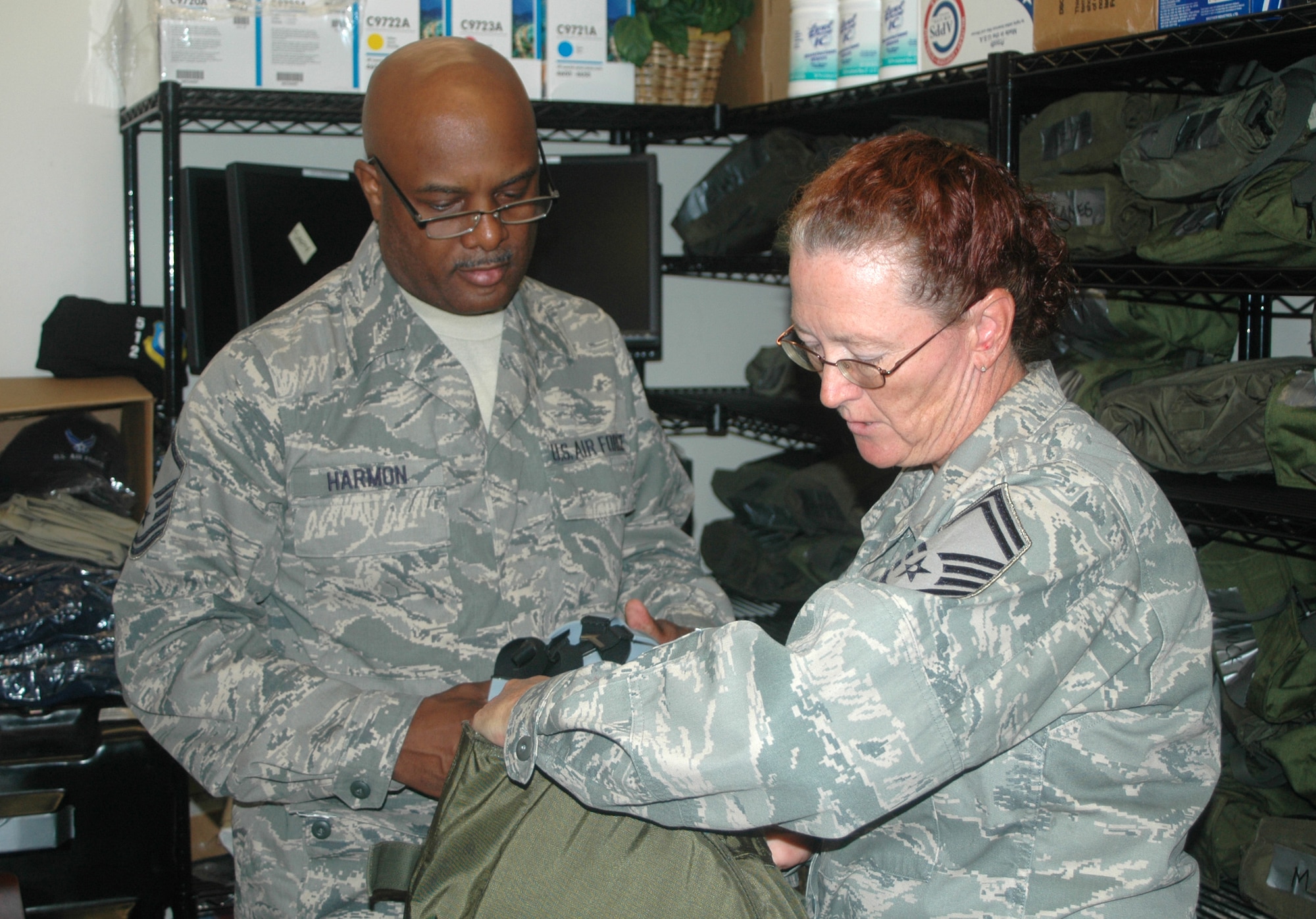 Master Sgt. Tony Harmon, (left), B Flight NCO in charge, 512th Memorial Affairs Squadron, Dover Air Force Base, Del., and Senior Master Sgt. Raenita Monroe, 512th MAS, training and readiness superintendent, inspect squadron members' protective masks here July 22, in preparation for the August unit training assembly. Reservists assigned to the 512th MAS have the unique mission of supporting the installation's dining facility, fitness center and lodging facilities, while providing the Air Force Mortuary Affairs Operation Center here with Air Force Reserve Command's biggest Port Mortuary support team. (U.S. Air Force photo/Master Sgt. Jake Chappelle)
