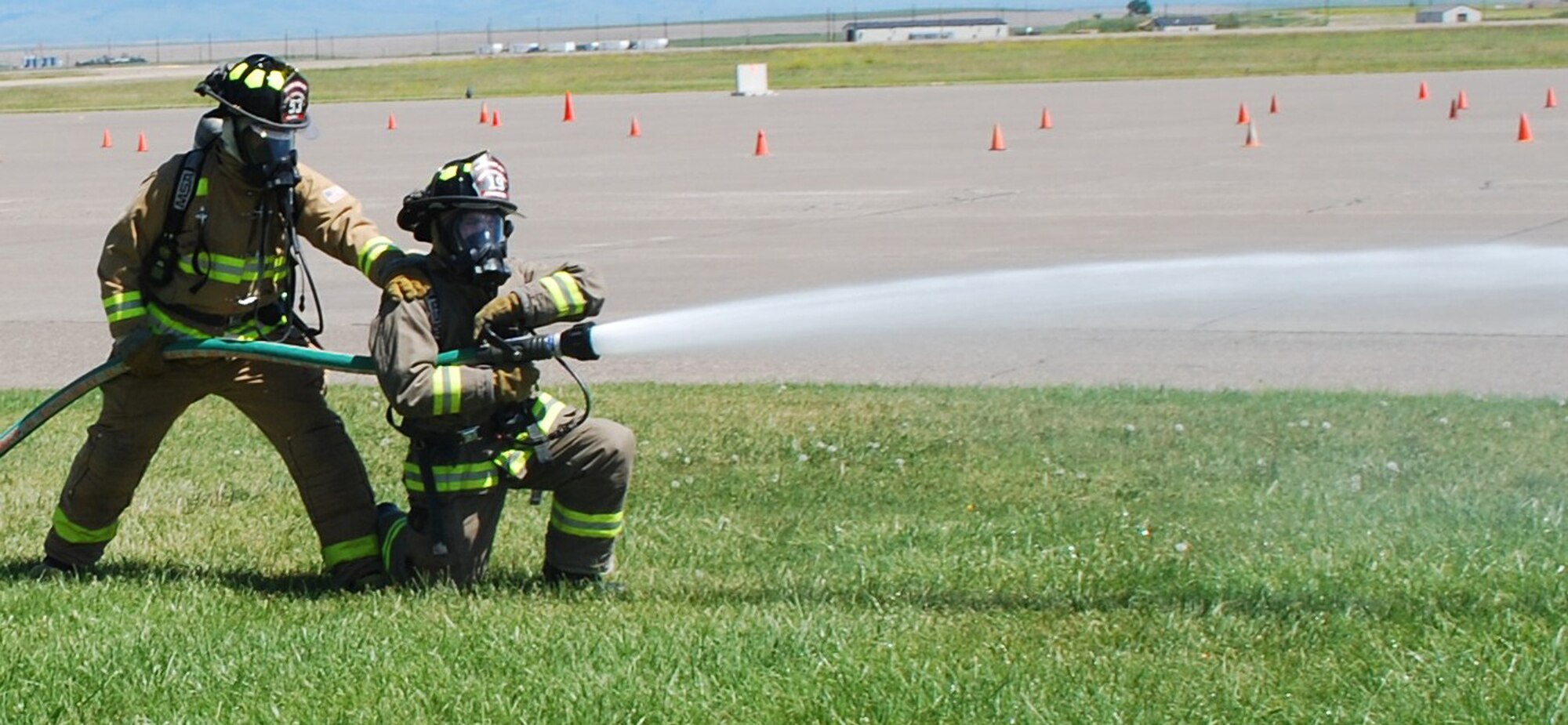 Senior Airman Zachary Henry and Airman 1st Class Nathan Johnson, 341st Civil Engineering Squadron firefighters, execute hand line training to increase their familiarity with water pressure and practice proper handling techniques during training at the base fire department July 8. (U.S. Air Force photo/Airman 1st Class Kristina Overton)