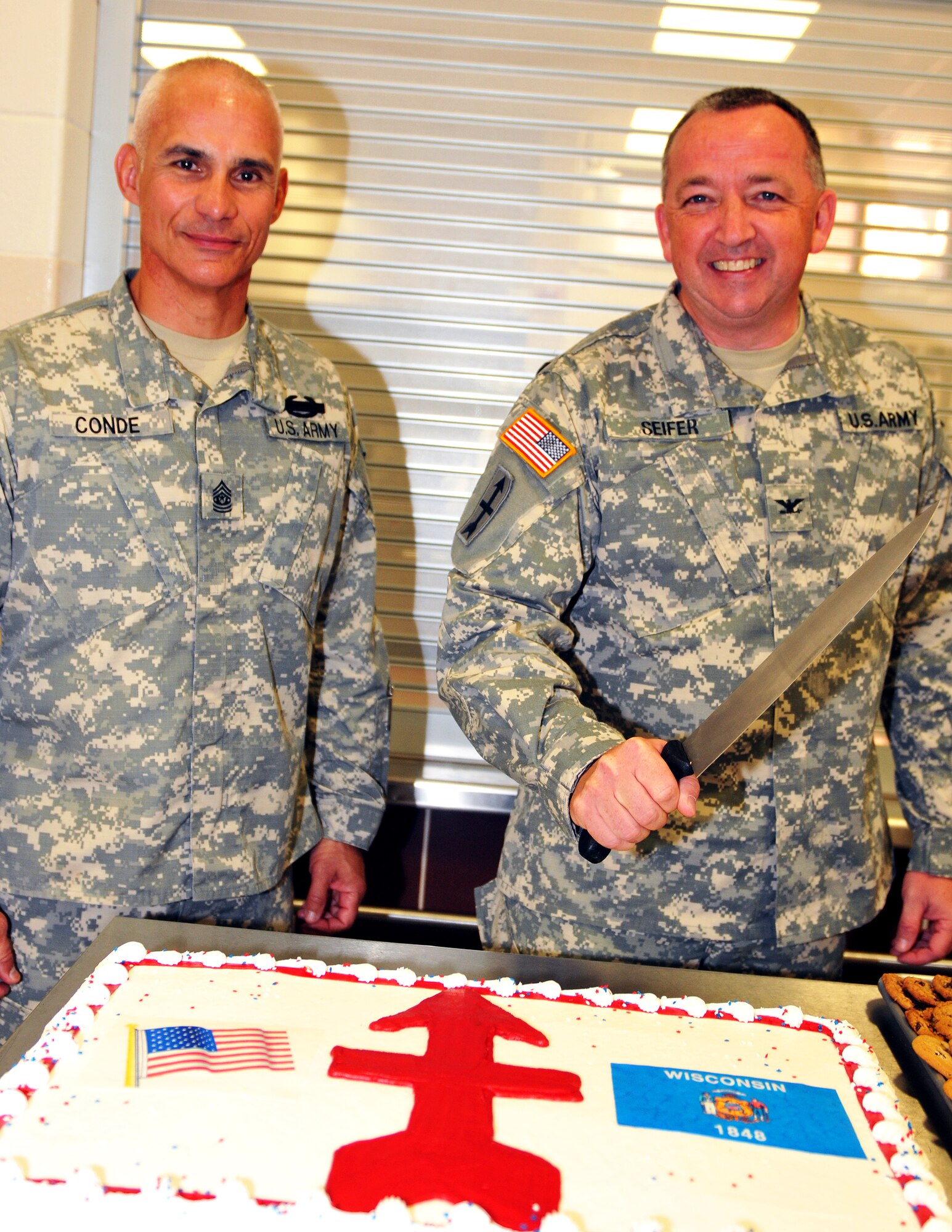 Command Sgt. Maj. Rafael Conde and Col. Martin Seifer, 32nd Infantry Brigade Combat Team command sergeant major and commander, prepare to cut the official cake during a change-of-command ceremony at Camp Williams July 10. Wisconsin National Guard photo by Tech. Sgt. Jon LaDue 
