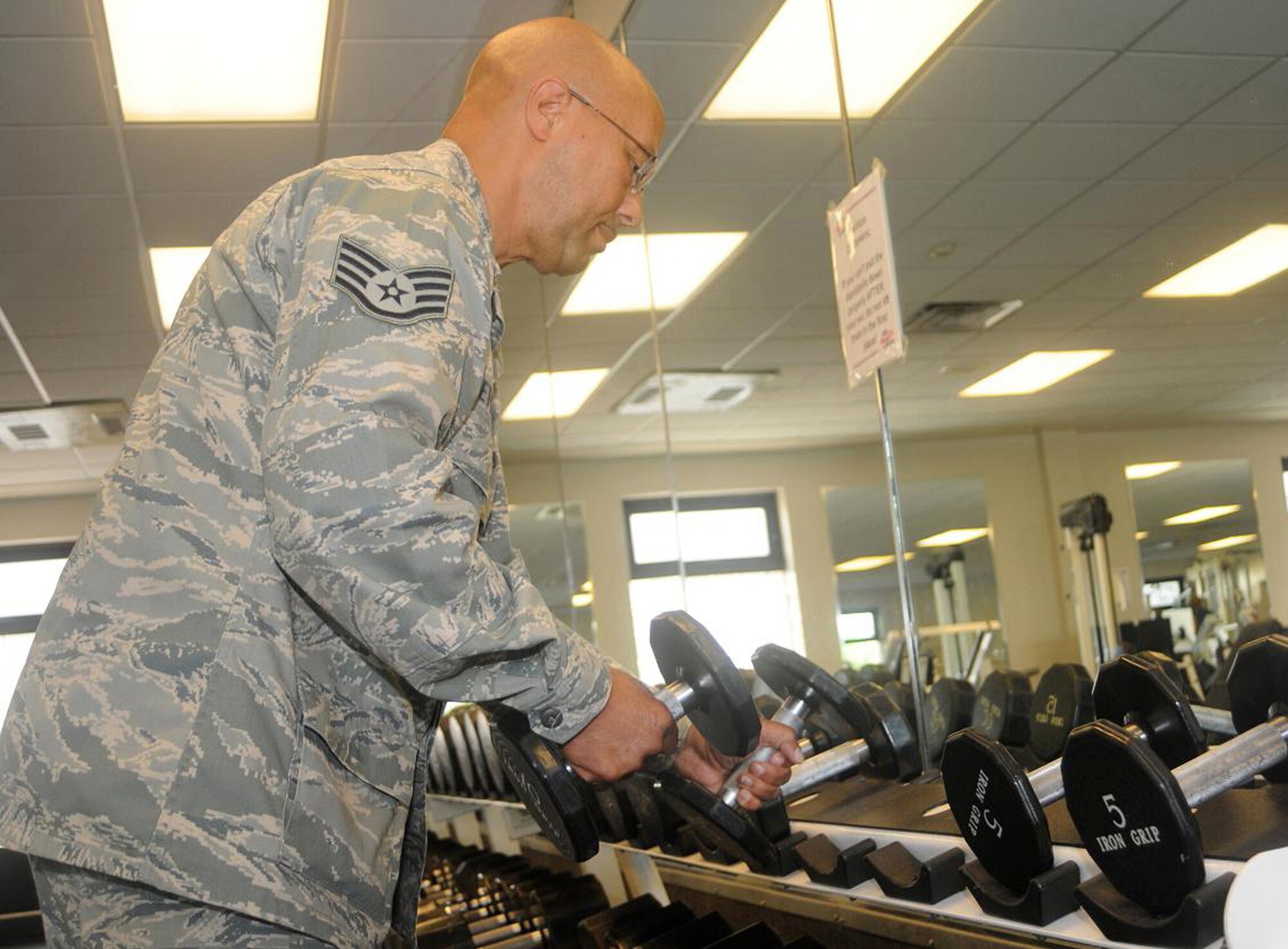 Staff Sgt. Keith Fletcher, 512th Memorial Affairs Squadron, Dover Air Force Base, Del., fitness supervisor, realigns dumbbells to their designated places on the dumbbell stand at the base fitness center here June 6. Sergeant Fletcher said he likes to stay fit himself, and enjoys helping Airmen reach their full fitness potential through appropriate training. (U.S. Air Force photo/Senior Airman Bhawan P. Singh)