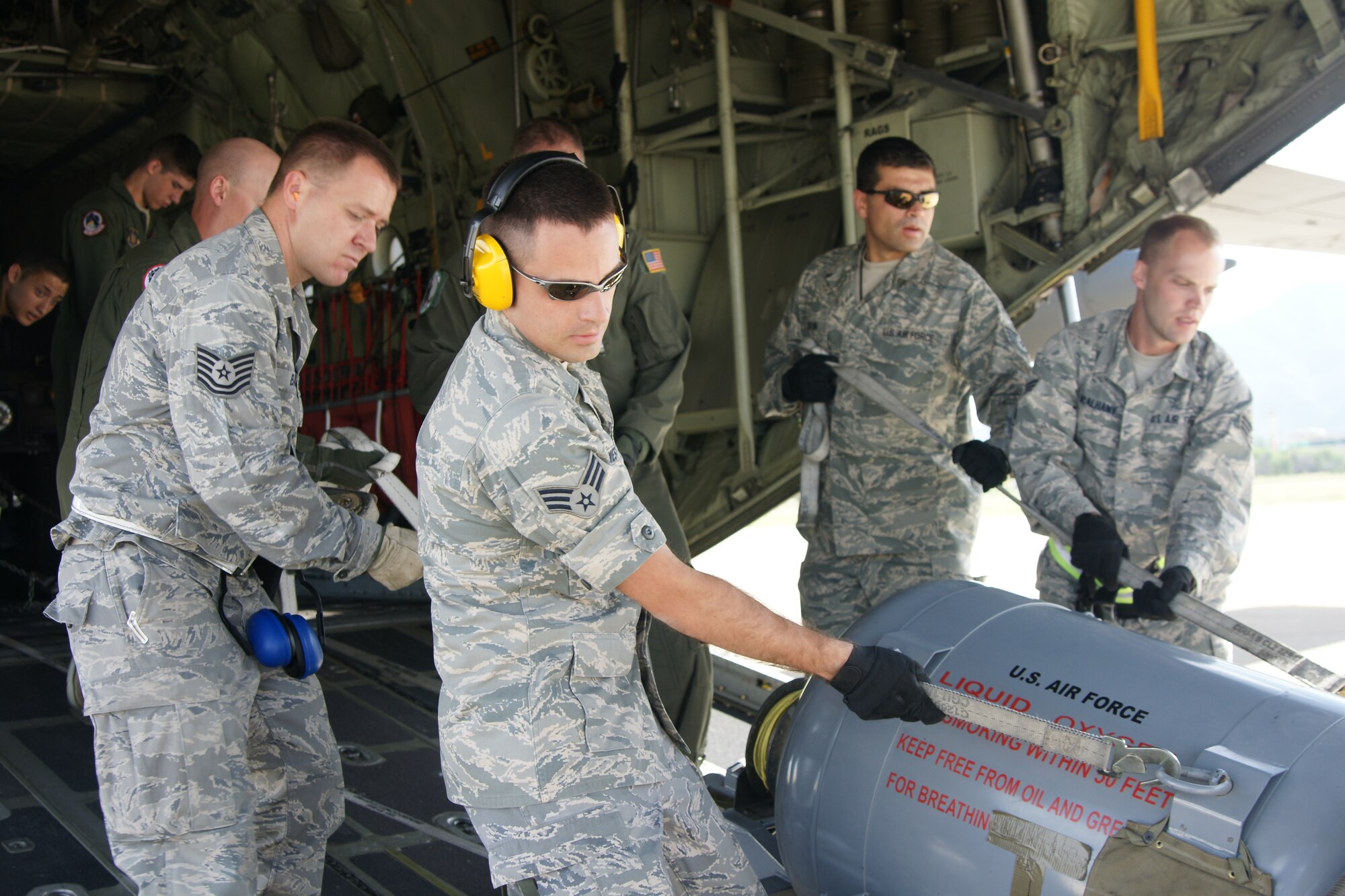 Members of the 67th Aerial Port Squadron carefully lower a heavy concentrated oxygen tank down the cargo ramp of a C-130. (U.S. Air Force photo/Staff Sgt. Alan Schultz)