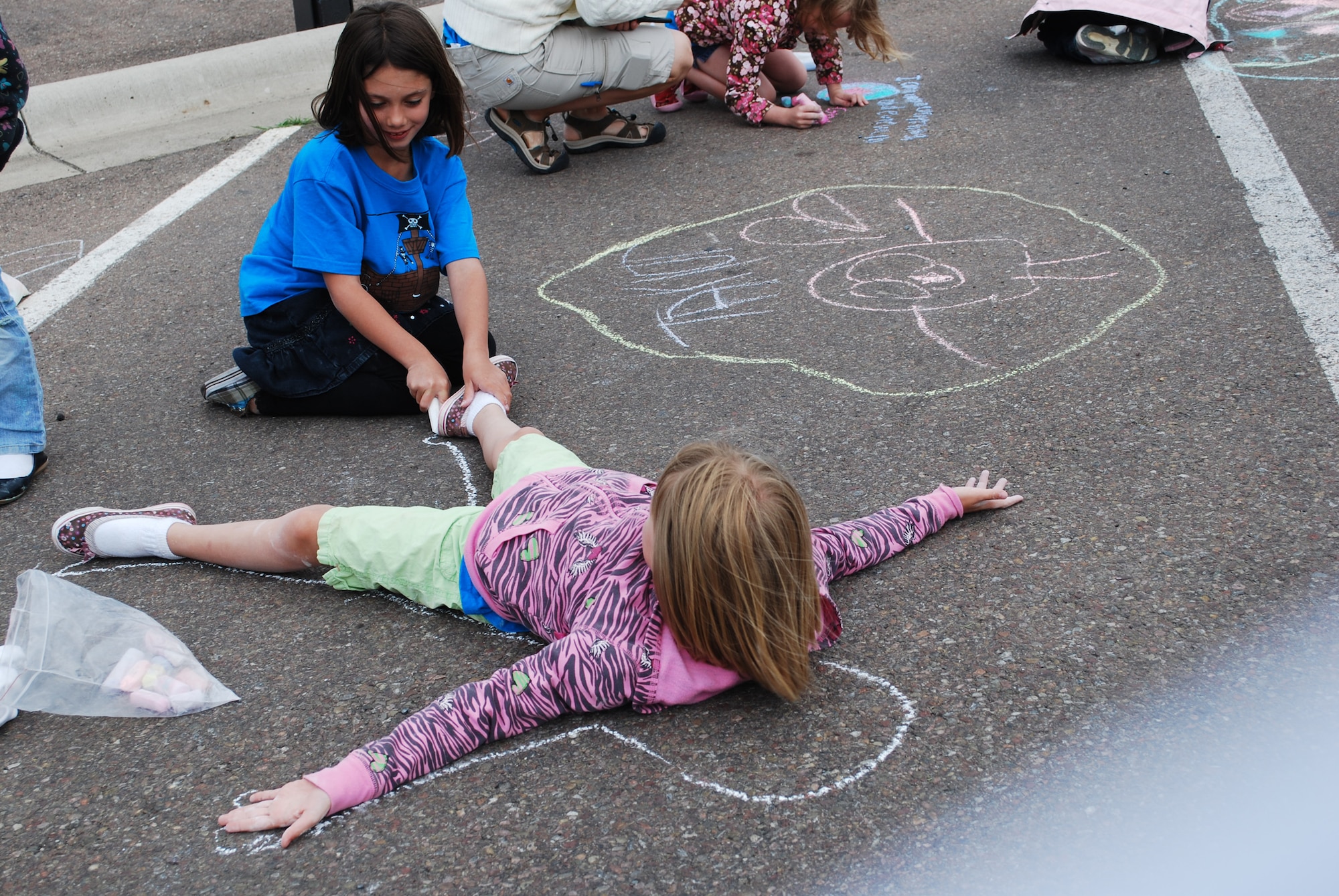 Little Warrior Hailey, 7, sketches a chalk outline around Little Warrior Jordyn, 8. (U.S. Air Force photo/Airman 1st Class Kristina Overton)