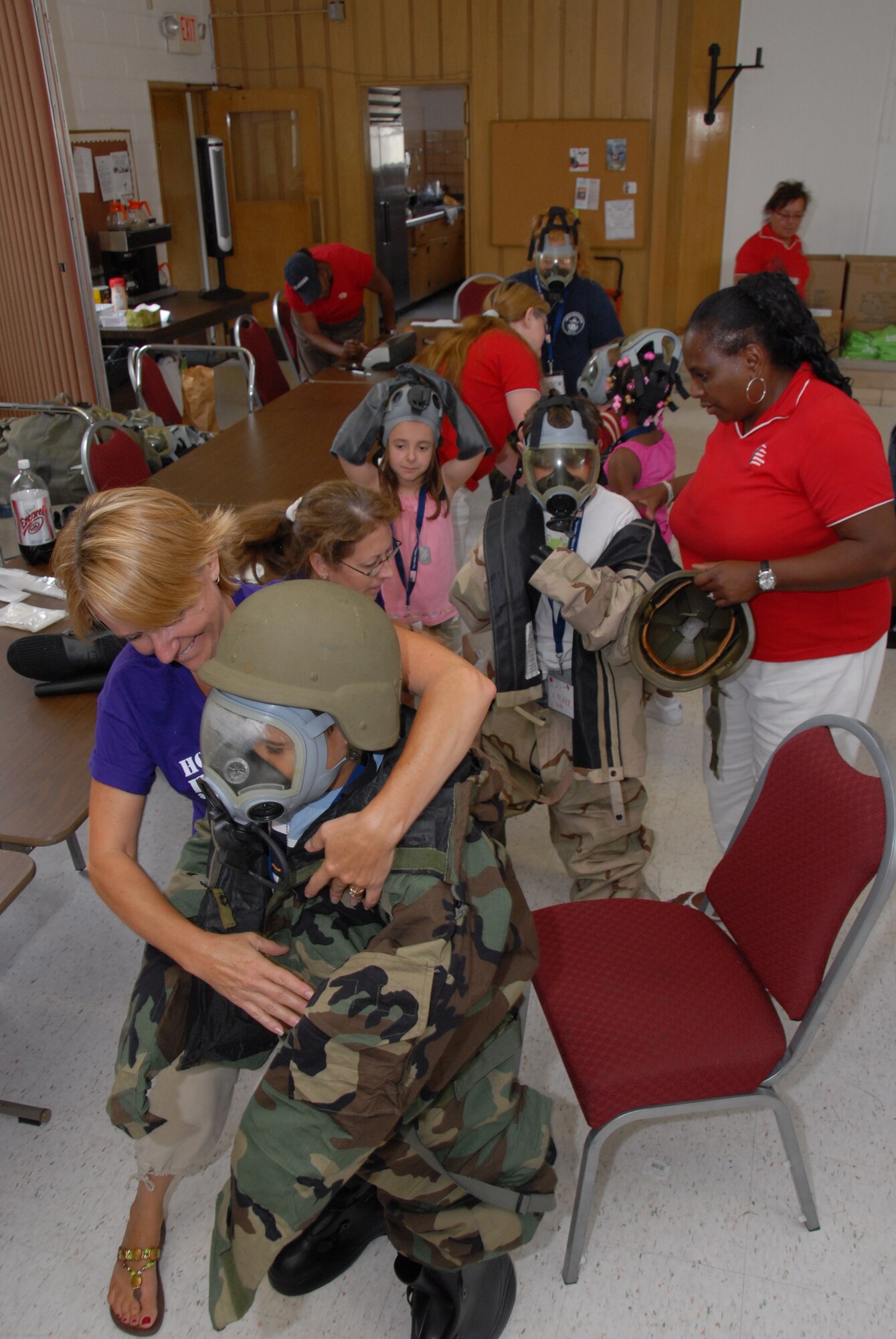 Deborah Schroeder, Selfridge Family Readiness director, and her staff help children from the Operation Purple Camp program try on military protective gear during a day-camp held at Selfridge Air National Guard Base, Mich., on July 17. Operation Purple Camp was designed for children of military members with parents who are deployed or will deploy to help the children develop and maintain healthy  relationships in spite of the current military deployment tempo. The children participated with arts and crafts, ran an obstacle course, went through a mock deployment line, played games, and toured select areas of the base. 