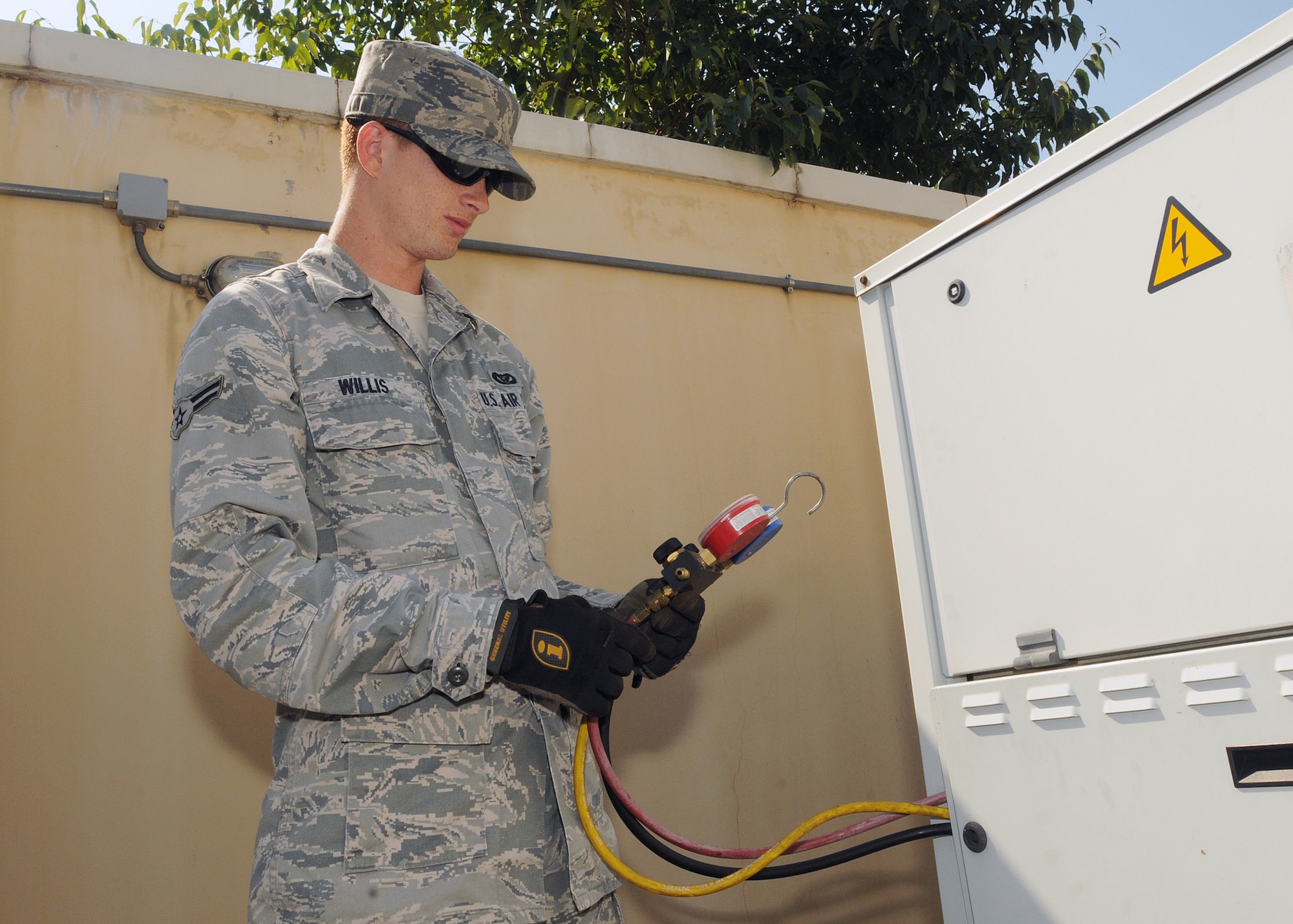 Airman 1st Class Corey Willis, 31st Civil Engineer Squadron heating, ventilation, air conditioning and refrigeration apprentice, examines manifold gauges outside a dormitory complex July 21.  These gauges verify the refrigerant pressure of the air conditioning unit.  (U.S. Air Force photo/Senior Airman Tabitha M. Lee)