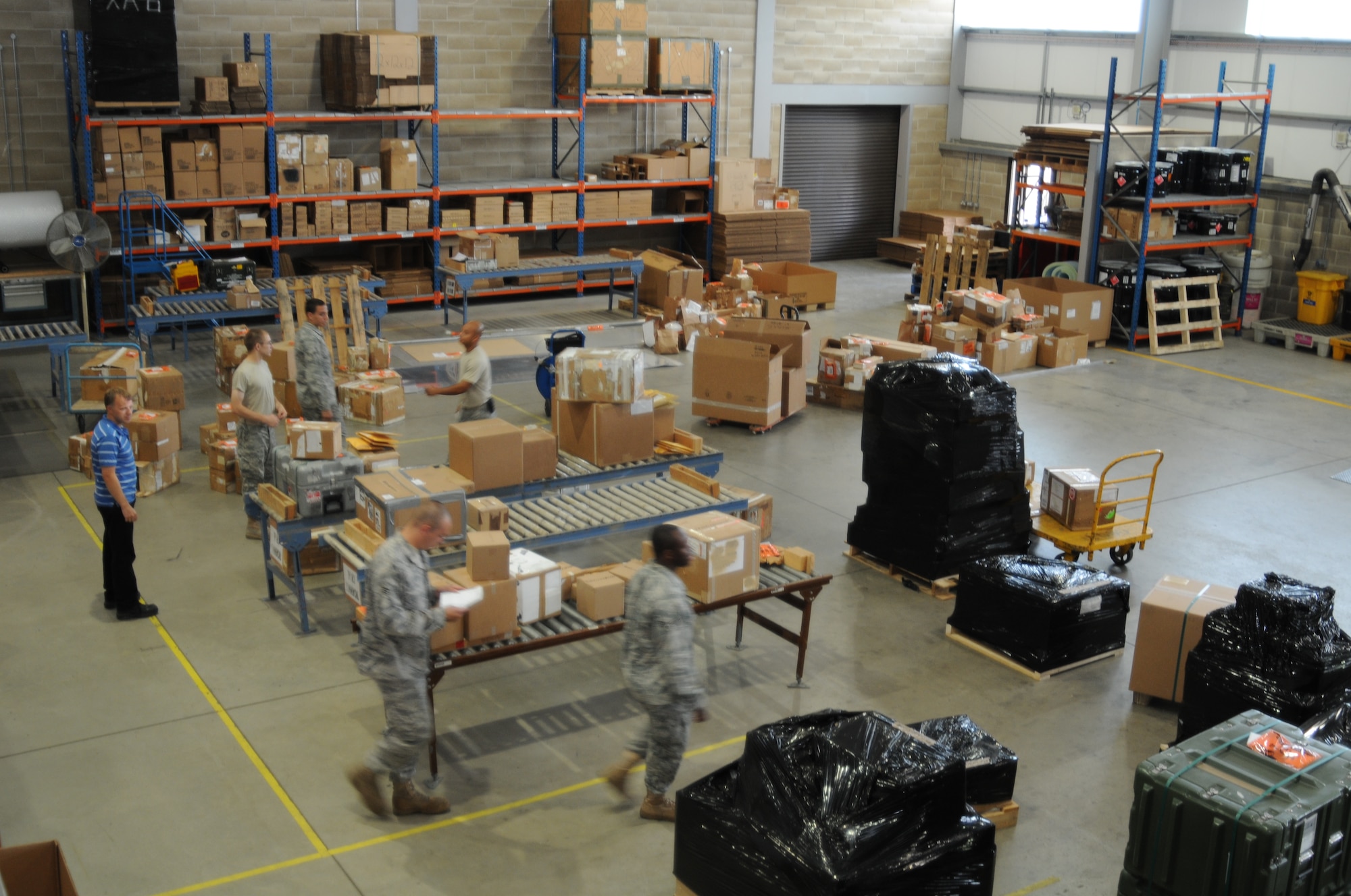 Both Airmen and Ministry of Defence personnel process packages in the Traffic Management Office warehouse July 19. TMO is responsible for all incoming or outgoing government shipments on RAF Lakenheath. (U.S. Air Force photo/Senior Airman David Dobrydney)