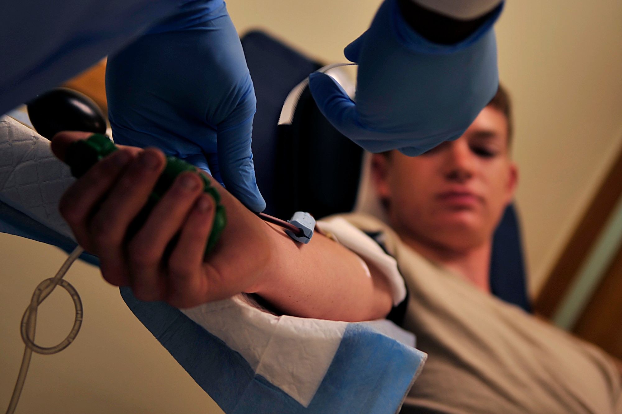 Army Sgt. Robert Weaver, 10th Support Group, begins the process of taking blood from Airman 1st Class Kyle Householder, 909th Aircraft Maintenance Unit, at the First Term Airman Center on Kadena Air Base July 21. (U.S. Air Force photo / Senior Airman Amanda Grabiec)