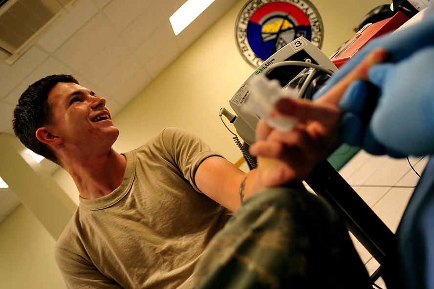 Petty Officer 2nd Class Anthony Quinones, Navy hospital corpsman from Camp Lester, takes a small amount of blood to test the hemoglobin in the plasma from Airman 1st Class Kyle Householder, 909th Aircraft Maintenance Unit, at the First Term Airman Center on Kadena Air Base July 21. (U.S. Air Force photo / Senior Airman Amanda Grabiec)