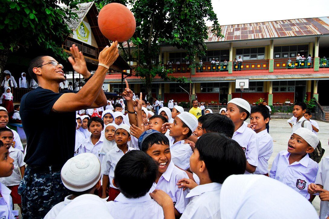 U.S. Navy Petty Officer 3rd Class Matthew Jackson teaches children how to spin a basketball on their fingertip during a Pacific Partnership 2010 community service event at Kalumpang Kota Orphanage and School in Ternate, Indonesia, July 19, 2010.