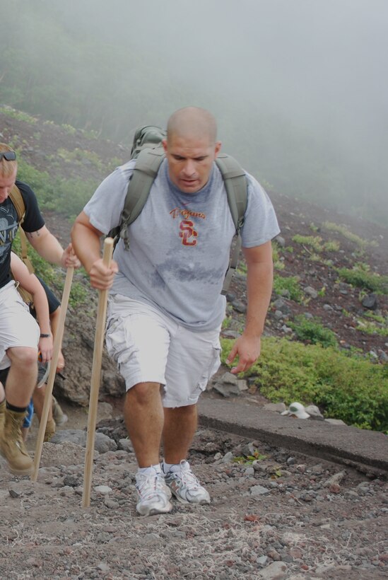 Aircraft Rescue Fire Fighting section leader, Staff Sgt. Shane Waiau, uses his walking stick to climb the steps to the seventh station of Mt. Fuji July 24. Climbers can purchase walking sticks at the base or various stations of the mountain as well as special stamps, which are branded onto the sticks to mark each accomplished checkpoint.