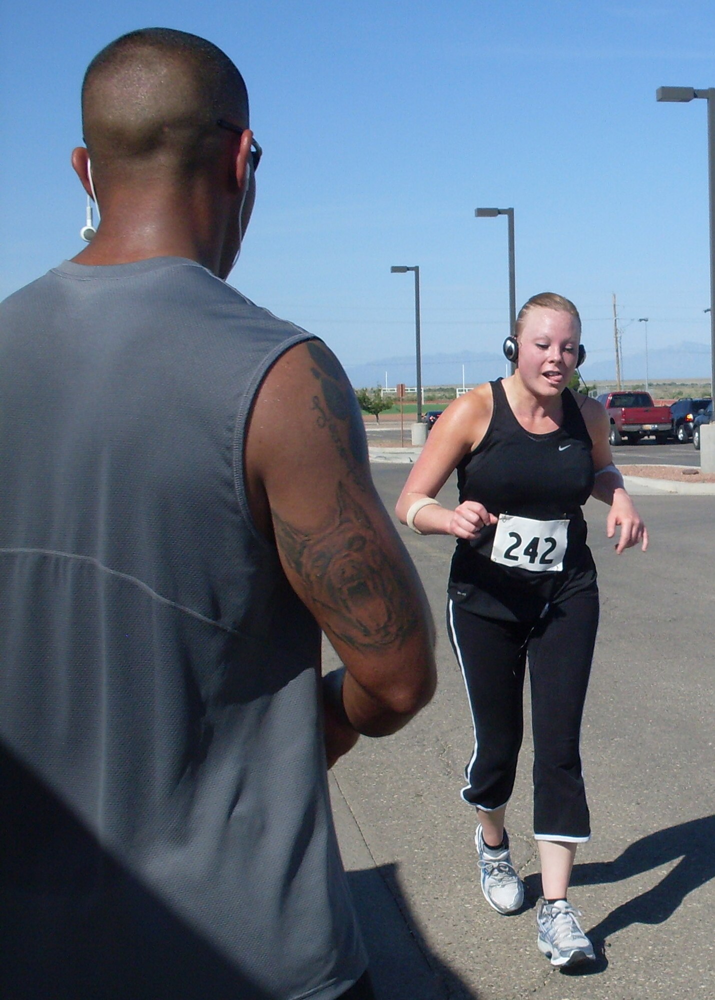 HOLLOMAN AIR FORCE BASE, N.M. -- Staff Sgt. Shiloh Bell, 49th Security Forces Squadron, is greeted by Staff Sgt. Daniel Flores, 49th Security Forces Squadron Military Working Dog Flight, as she jogs to the finish line during the Half Marathon at the Domenici Fitness and Sports Center July 17, 2010. Sergeant Bell came in third place in the women's category of the 13.2 mile race. (Courtesy photo)