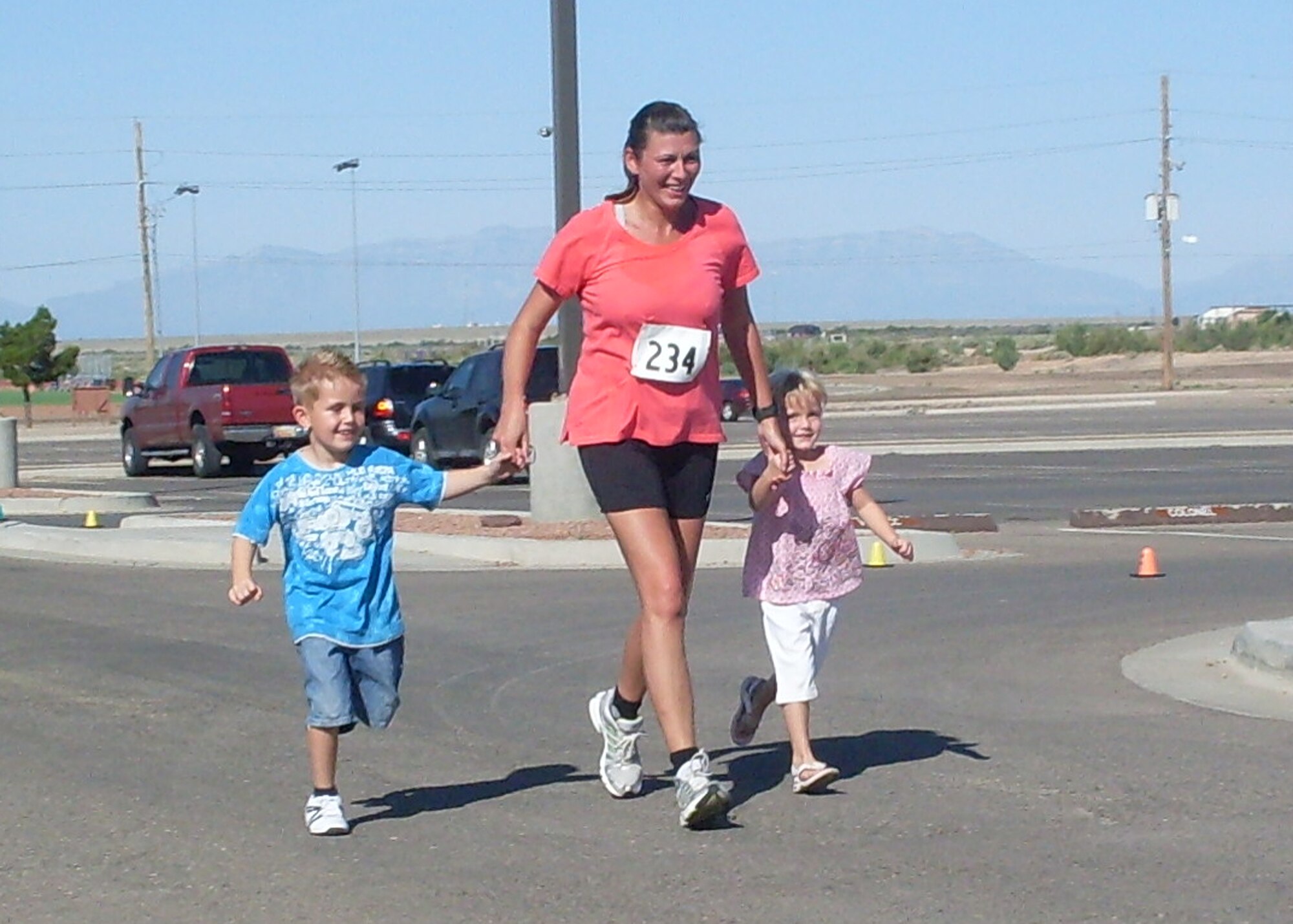 HOLLOMAN AIR FORCE BASE, N.M. -- Master Sgt. Tanja Schmidt, German Air Force Flying Training Center, crosses the finish line with her children during the Half Marathon at the Domenici Fitness and Sports Center July 17, 2010. Sergeant Schmidt finished in first place in the women's category of the 13.2 mile race. (Courtesy photo)
