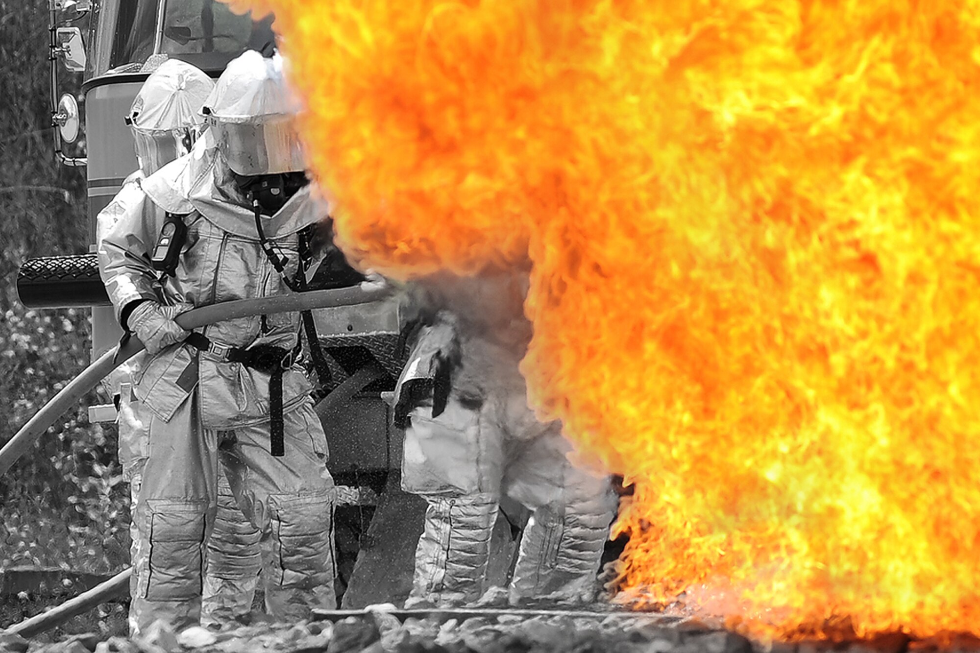 Firefighters battle a roaring fire while participating in a aircraft 'crash' during a live fire response exercise held at the Combat Readiness Training Center at Alpena, Mich., July 21, 2010. The firefighters are with the Michigan Air National Guard's 127th Wing at Selfridge Air National Base.   (U.S. Air Force photo illustration/Master Sgt. Terry Atwell)