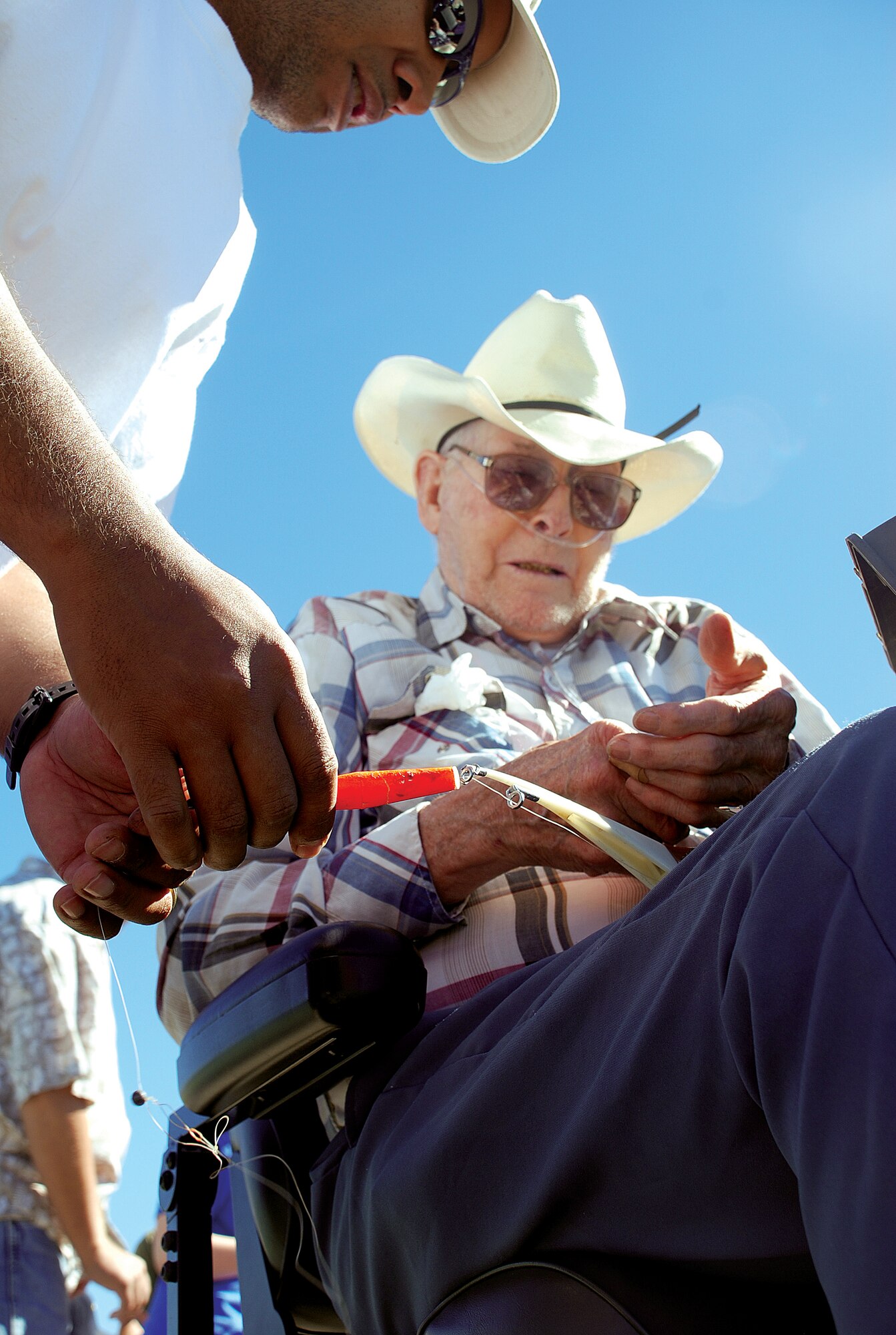 Tech. Sgt. Brian Kellergriffin, 90th Logistics Readiness Squadron, assists Swede Oline, a retired veteran, set-up his line during the fishing day July 16. (U.S. Air Force photo by Staff Sgt. Mike Tryon)