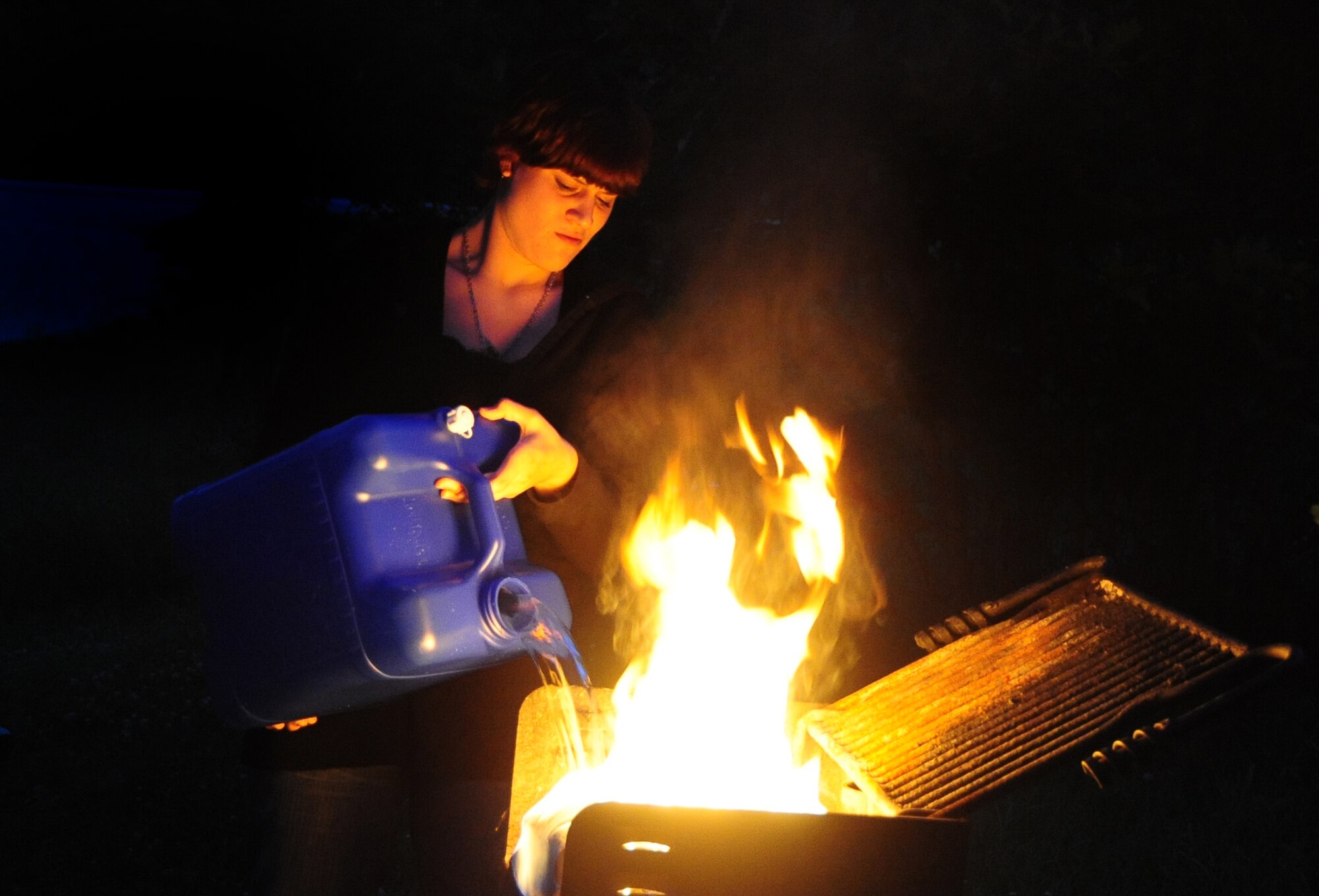 ELLSWORTH AIR FORCE BASE, S.D. -- Airman Megan Dix, Air Force Financial Services Center travel technician, pours water onto a fire in a camp grill at Spring Creek, S.D., July 22.  It is imperative to completely put out a fire before walking away from it to keep the fire from re-igniting. (U.S Air Force photo/Airman 1st Class Anthony Sanchelli)