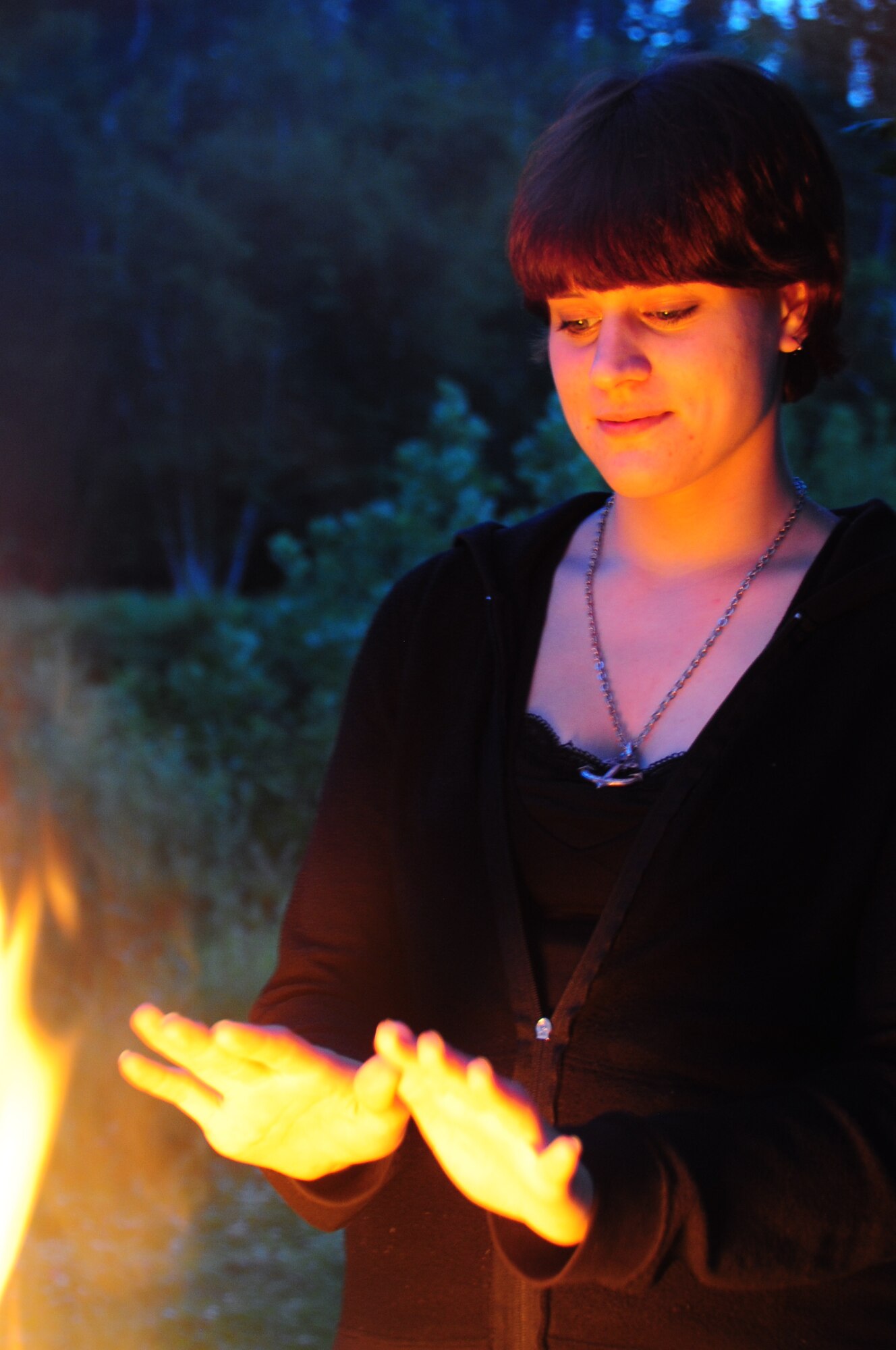 ELLSWORTH AIR FORCE BASE, S.D. -- Airman Megan Dix, Air Force Financial Services Center travel technician, warms her hands by a fire in a camp grill at Spring Creek, S.D., July 22.  It's important when having a fire to keep it under control so it doesn’t start a wild fire. (U.S Air Force photo/Airman 1st Class Anthony Sanchelli)