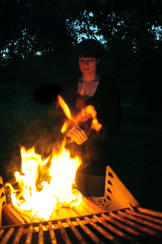 ELLSWORTH AIR FORCE BASE, S.D. -- Airman Megan Dix, Air Force Financial Services Center travel technician, warms her hands by a fire in a camp grill at Spring Creek, S.D., July 22.  Airman Dix stays a safe distance away from the flames to keep from getting burned. (U.S Air Force photo/Airman 1st Class Anthony Sanchelli)