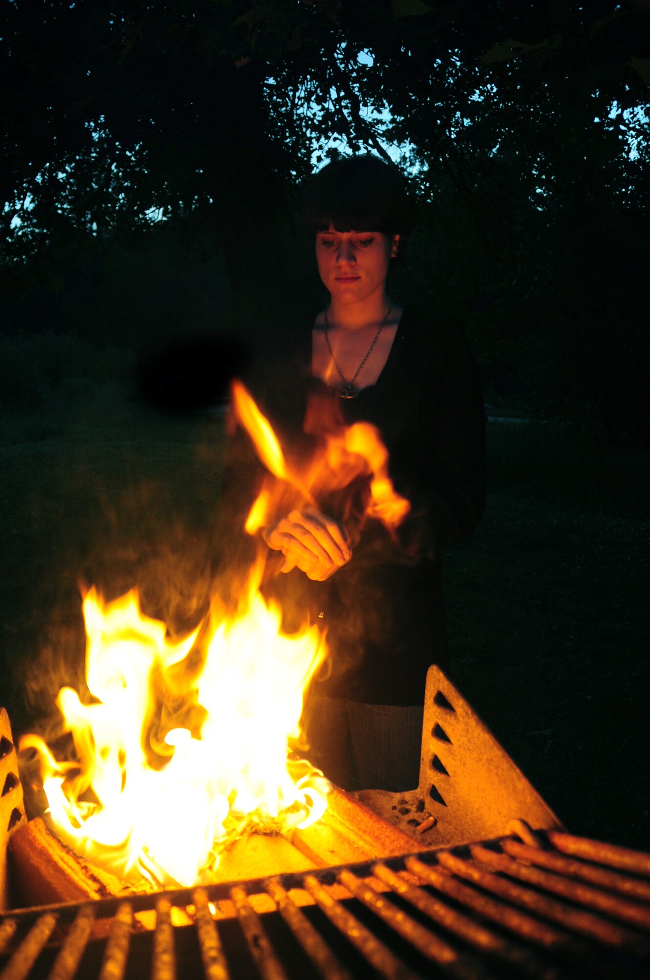 ELLSWORTH AIR FORCE BASE, S.D. -- Airman Megan Dix, Air Force Financial Services Center travel technician, warms her hands by a fire in a camp grill at Spring Creek, S.D., July 22.  Airman Dix stays a safe distance away from the flames to keep from getting burned. (U.S Air Force photo/Airman 1st Class Anthony Sanchelli)