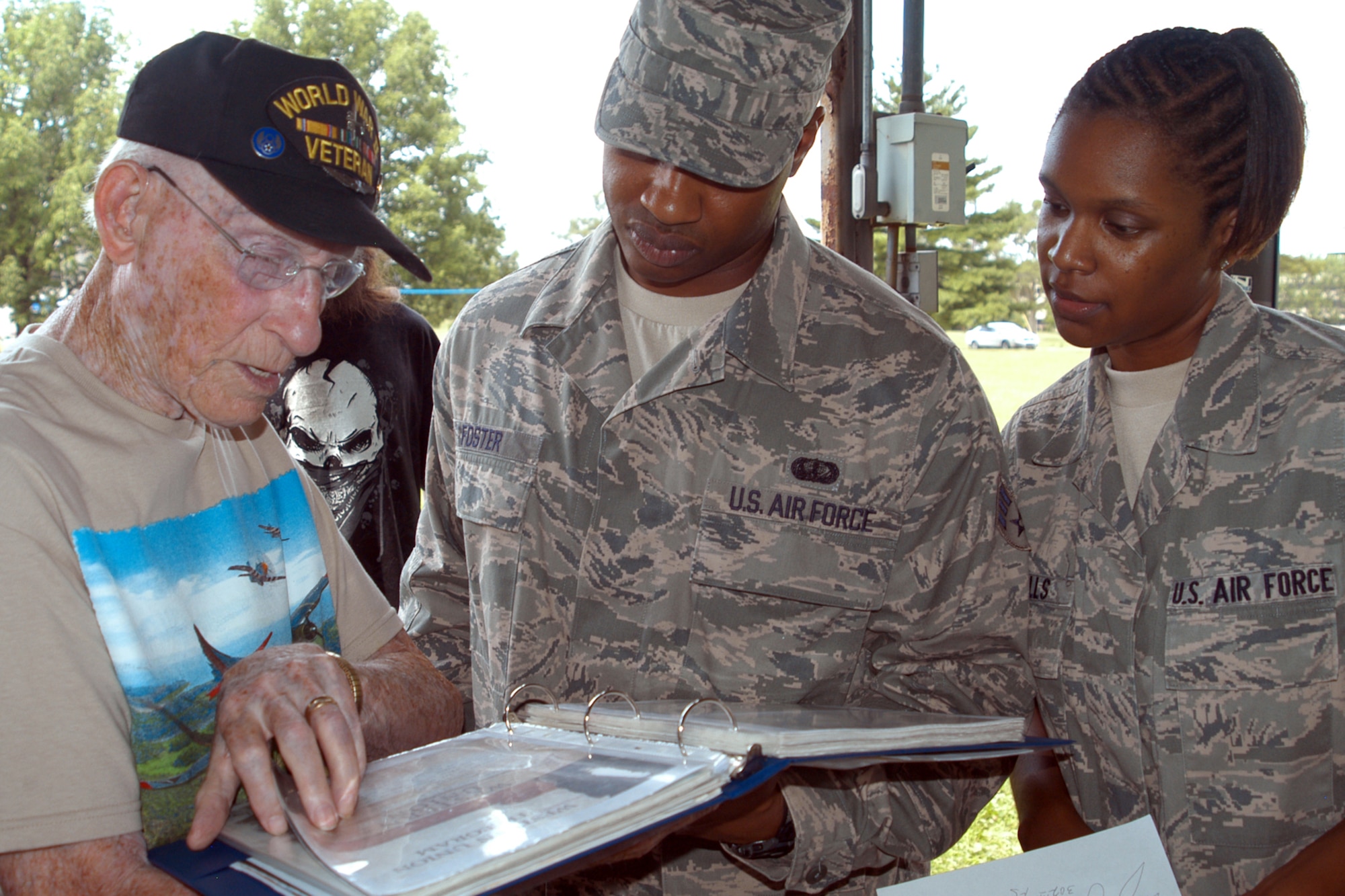 GRISSOM AIR RESERVE BASE, Ind., -- Charles Ormsby, an aerial engineer and gunner in the B-17, shows some of his scrapbook items to Senior Airmen DeShannon Foster, 434th Services Flight, center, and SrA. Jamia Nalls, 434th Civil Engineer Squadron,  during a "Voices of  History" luncheon held July 21 in the Grissom Aeroplex. (U.S. Air Force photo/Tech. Sgt. Douglas Hays)