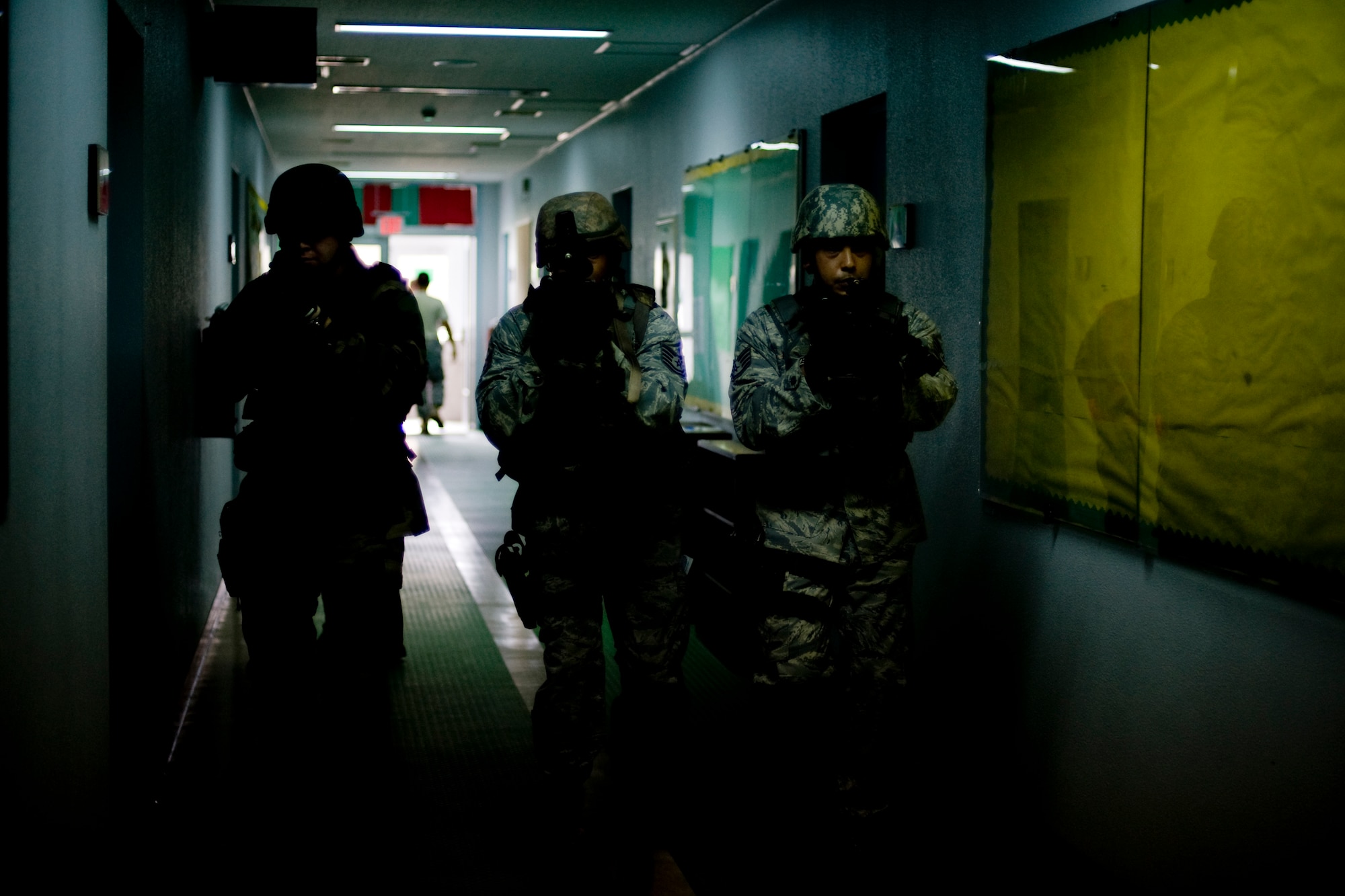 MISAWA AIR BASE, Japan -- Petty Officer 1st Class Robert Borders, Naval Air Facility security operations supervisor, and Tech. Sgt. Christopher Jones and Staff Sgt. Dennis Mathys, both with the 35th Security Forces Squadron, make their way through a dimly lit Robert D. Edgren High School hallway July 23 during high-risk response training. Poor lighting conditions, props and role players made for a realistic training environment geared to test students' quick-response actions. (U.S. Air Force photo/Senior Airman Jamal D. Sutter)