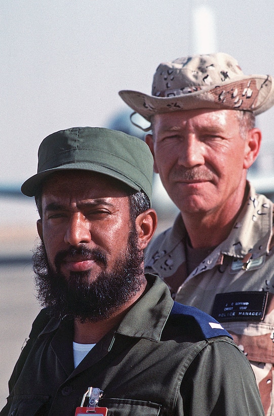 U.S. Air Force Chief Master Sgt. James Goffard and Saudi Arabian Army Chief Warrant Officer Ali Abdulaziz Al-Hamdan pose for a photograph at a desert base camp. The Saudi Arabian veteran soldier assists military efforts by acting as a liaison between American and Saudi forces during Operation Desert Shield.