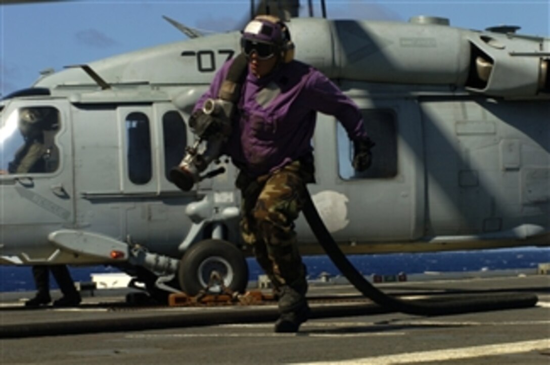 U.S. Navy Airman Carlos Gomez retrieves fuel lines after refueling an HS-60 Seahawk helicopter on the flight deck of the amphibious transport dock ship USS Cleveland (LPD 7) underway in the Pacific Ocean supporting Rim of the Pacific on July 19, 2010.  Rim of the Pacific is a biennial, multinational exercise to strengthen regional partnerships and improve multinational interoperability.  
