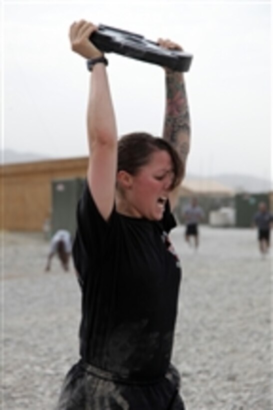 A U.S. Army soldier completes her 20th repetition with a 25-pound weight while taking part in the One Shot, One Kill workout program at Forward Operating Base Shank, Logar province, Afghanistan, on July 20, 2010.  