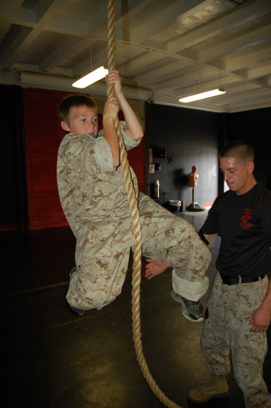 Eleven-year-old Riley Lamberson attempts to climb a rope with the support of Sgt. Christopher Taylor, chief Marine Corps Martial Arts instructor, Weapons and Field Training Battalion and a Scottsburg, Ind., native. Riley, who has cystic fibrosis, spent a day with Marines at Marine Corps Base Camp Pendleton, Calif. July 23, as part of his wish with the Make-a-Wish Foundation. (Official Marine Corps photos by Staff Sgt. Marc Ayalin)