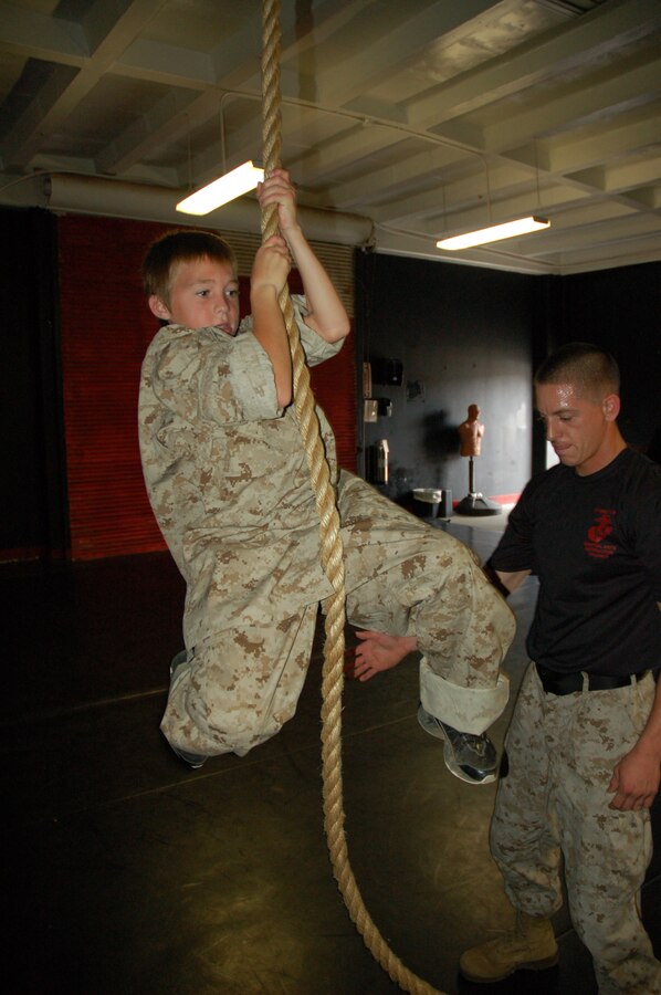 Eleven-year-old Riley Lamberson attempts to climb a rope with the support of Sgt. Christopher Taylor, chief Marine Corps Martial Arts instructor, Weapons and Field Training Battalion and a Scottsburg, Ind., native. Riley, who has cystic fibrosis, spent a day with Marines at Marine Corps Base Camp Pendleton, Calif. July 23, as part of his wish with the Make-a-Wish Foundation. (Official Marine Corps photos by Staff Sgt. Marc Ayalin)