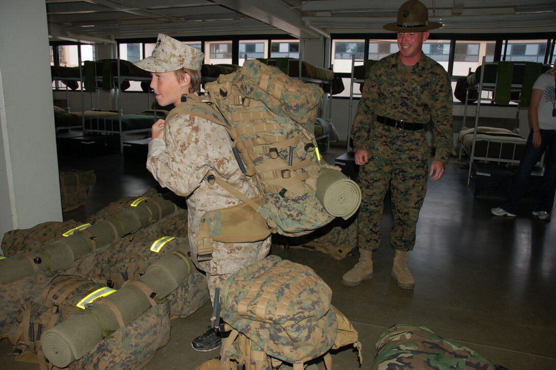 Eleven-year-old Riley Lamberson dons a pack to get a feel of what Marine recruits undergo as Sgt. Brently Bishop, senior drill instructor, Platoon 1053, Company C, 1st Battalion, Recruit Training Regiment, supervises. Riley, who has cystic fibrosis, spent a day with Marines at Marine Corps Base Camp Pendleton, Calif., July 23, as part of his wish with the Make-a-Wish Foundation. (Official Marine Corps photos by Staff Sgt. Marc Ayalin)