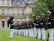 Lance Cpl. Nicholas Meekins and Lance Cpl. Michael Hintz simultaneously spin rifles during a performance at the U.S. Ambassador's House in Paris, France.