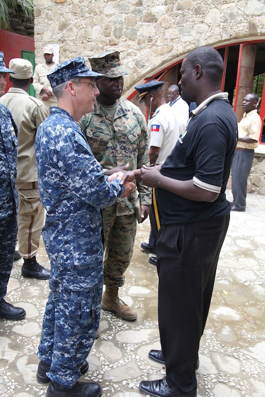 Navy Capt. Thomas M. Negus, commodore of USS Iwo Jima, and translator Staff Sgt. Vladimyr Merci, a native of Liancourt, Haiti, shake hands with Pardin Francois, director of Lycee Guillaud Haitian School, July 24, 2010, in Port-de-Paix, Haiti. USS Iwo Jima Marines and Sailors visited the Haitian school as part of a site mission visit in Port-de-Paix in preparation for military personnel and non-government officials to conduct humanitarian civic assistance as part of Operation Continuing Promise 2010.