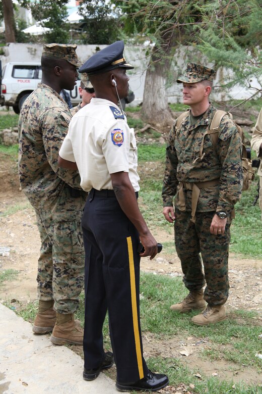 Jean Moise, chief of Port-de-Paix, Haiti National Police, speaks with Lt. Col. Chris S. Richie, commanding officer of Special-Purpose Marine Air-Ground Task Force Continuing Promise 2010, and Staff Sgt. Vladimyr Merci, a native of Liancourt, Haiti, July 24, 2010. Haiti National Police led Marines and Sailors of the USS Iwo Jima throughout Port-de-Paix as they visited each mission site where military personnel will conduct medical, dental and community relations during their time in Haiti.