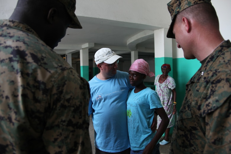 Staff Sgt. Vladimyr Merci, left, a native of Liancourt, Haiti, and Lt. Col. Chris S. Richie, commanding officer of Special-Purpose Marine Air-Ground Task Force Continuing Promise 2010, listen to a Northwest Haiti Christian Mission volunteer from the United States as he speaks about Servina, who has been living at the emission for three years.  The Northwest Haiti Christian Mission has been designated as a site to receive engineering assistance as part of Operation Continuing Promise 2010.
