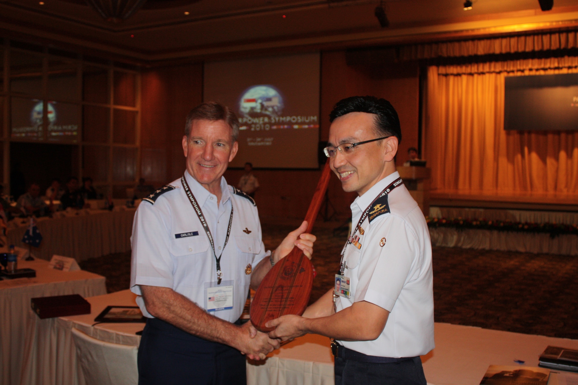 Lt. Gen. Hawk Carlisle, 13th Air Force commander, presents a Hawaiian Koa wood paddle to Brig. Gen. Kwek Kok Kwong, Commander of the Air Defence and Operations Command from the Republic of Singapore Air Force, during the PACRIM Airpower Symposium closing ceremonies.  The annual symposium encourages relationship building and enhances cooperation among the air forces of Asia-Pacific nations. This year's symposium theme, “The Role of Airpower in Peace Support Operations,” aims to help participants from 24 nations better understand how air forces can support peace-keeping missions in the region.  (U.S. Air Force photo/ Lt. Col. Ken Hoffman)