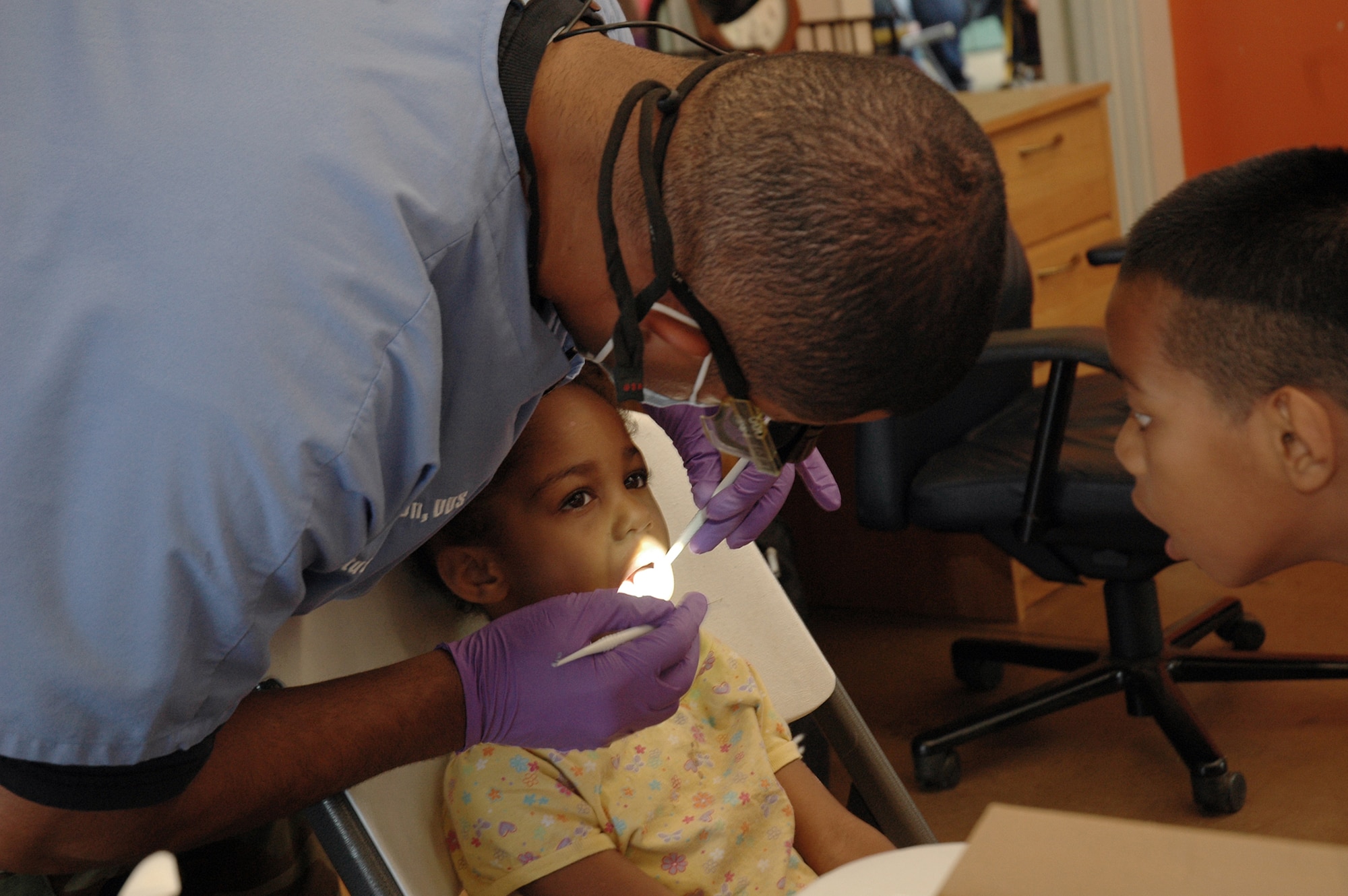 Maj. Stuart Thompson, 154th Medical Group, dentist, inspects young girl's teeth while her brother looks on during Hawaii Medical Innovative Readiness Training-community outreach in Waianae, Hawaii, July 16. Innovative Readiness Training is designed to give Guards members an opportunity to complete mission essential training while addressing community and civic needs. (U.S. Air Force photo/Tech. Sgt. Betty J. Squatrito-Martin)