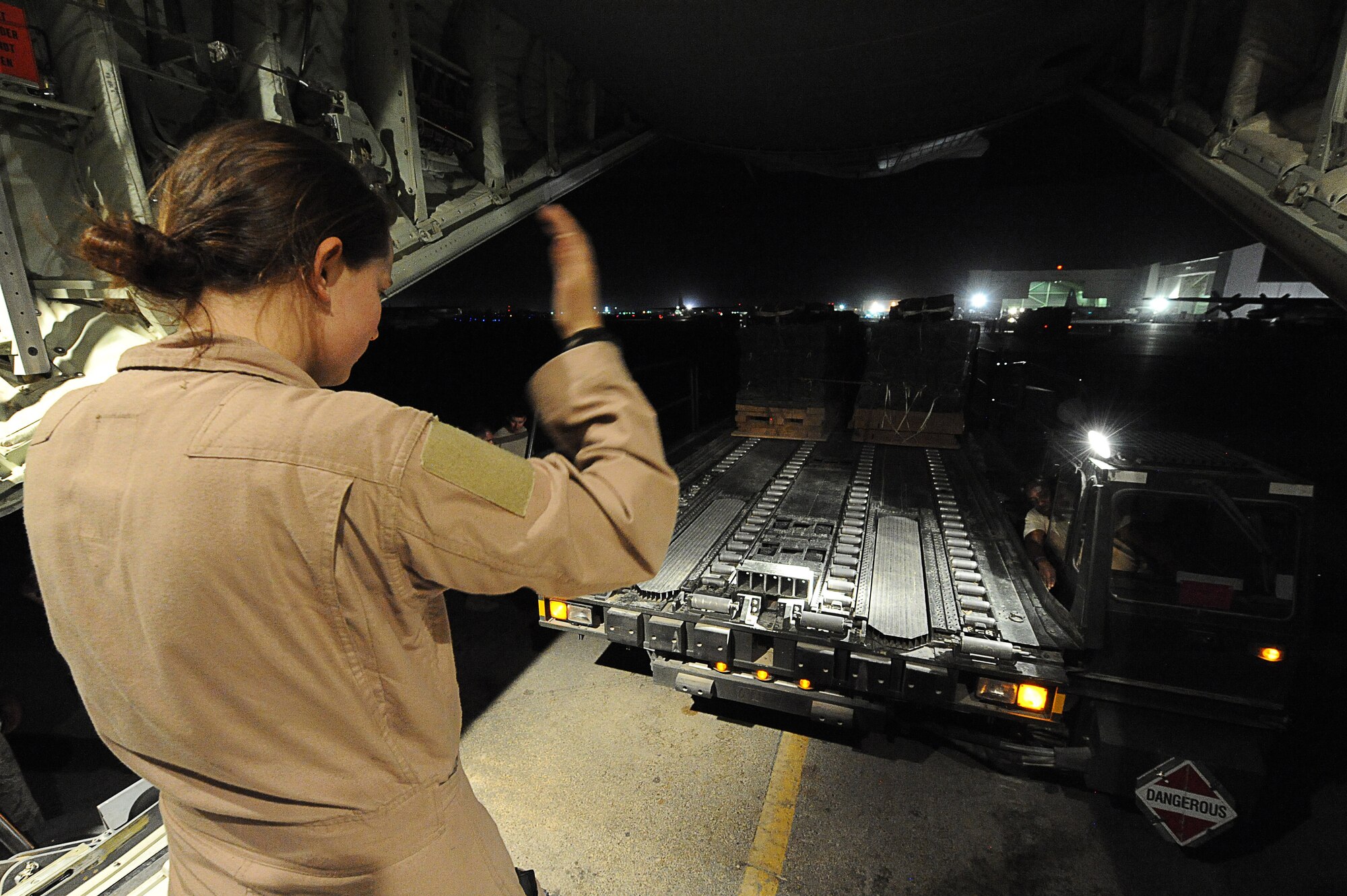 Airman 1st Class Racheal Orazine , a loadmaster assigned to the  772nd Expeditionary Airlift Squadron, Kandahar Airfield, Afghanistan,  guides a K-loader into position July 16, 2010.  Airman Orazine loads a C-130J Hercules with 16 bundles of supplies to be airdropped during a nighttime mission for soldiers in remote forward operating bases throughout Afghanistan.  (U.S. Air Force photo by Staff Sgt. Chad Chisholm/Released)