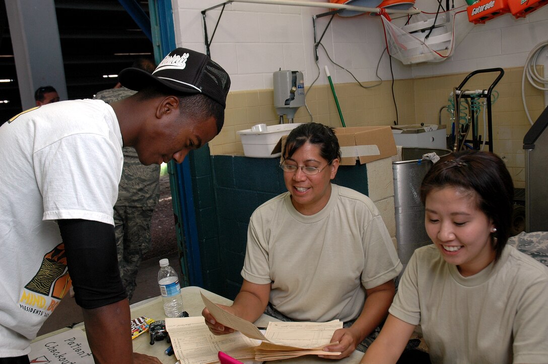 Master Sgt. Lisa Bartolome, health Services manager, 154th Medical Group and Staff Sgt. Jennifer Kim, medical materials, 154th Medical Group, check over sports physical paperwork with Waianae High School student athlete following his sports physical July 14, at Waianae High School. The sports physicals were part of the Department of Defense Innovative Readiness Training that took place from July 12-17, on the Leeward Coast of Oahu. (U.S. Air Force photo/Tech. Sgt. Betty J. Squatrito-Martin)