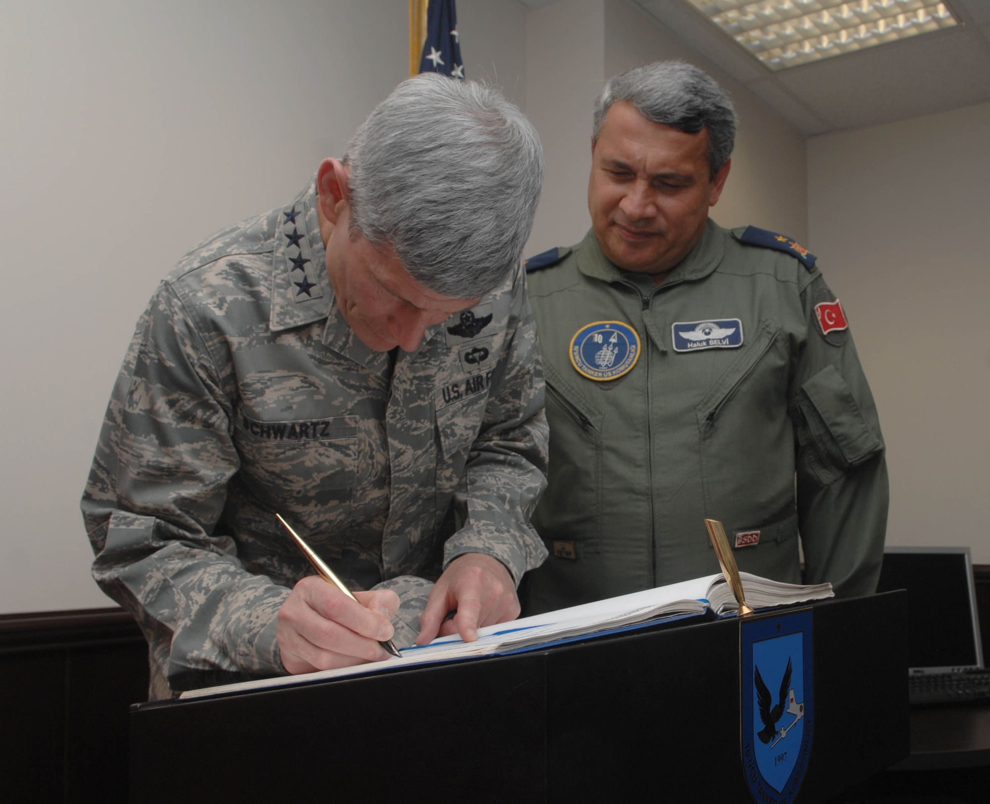 Brig. Gen. Haluk Selvi, 10th Tanker Base commander, observes as Gen. Norton Schwartz, the Air Force chief of staff, signs the honor book for the 10th Tanker Base Command, July 21, 2010 at Incirlik Air Base.  Signing the book is a 10th Tanker Base command tradition when distinguished visitors arrive here.  (U.S. Air Force photo/Tech. Sgt. Valda G. Wilson)