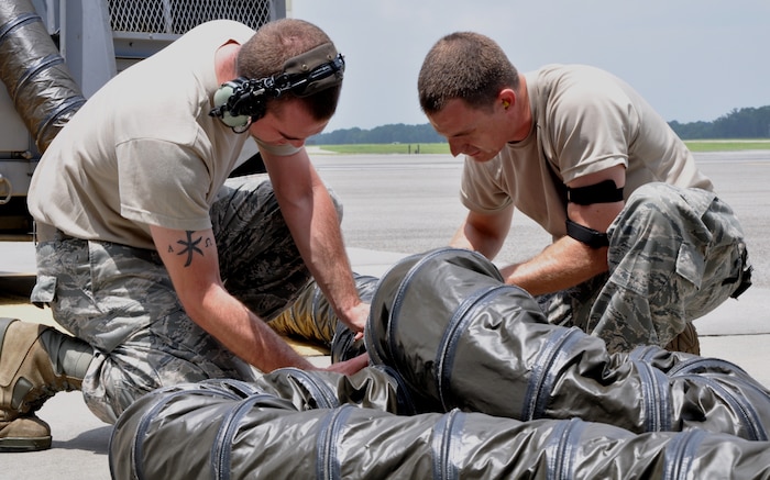 Staff Sgt. Charlie Watson and Senior Airman Jonathan Kiger work together to connect the air hose of a portable air conditioning unit to supply cool air inside the belly of a C-17 Globemaster III, July 23, 2010, at Charleston Air Force Base, S.C. Sergeant Watson is a communication and navigation specialist with the 315th Aircraft Maintenance Squadron here and Senior Airman Watson is a communication and navigation specialist with the 437th Aircraft Maintenance Squadron here. (U.S. Air Force photo/Staff Sgt. Shane Ellis)