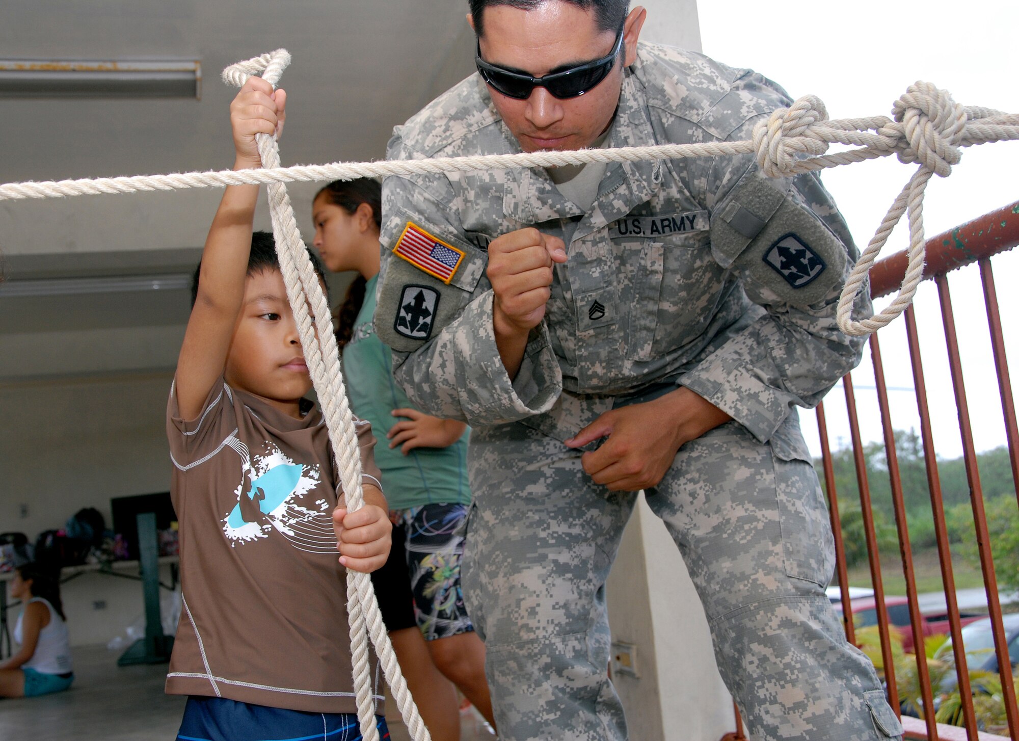Staff Sgt. Justen Laupola, Counterdrug Hawaii National Guard, gives young boy tips on tying a figure eight knot as part of the Drug Demand Reduction program on Guam, June 29. The DDR program is part of the National Guard's Counterdrug Program that emphasizes education and training as part of its drug abuse prevention program. (U.S. Air Force photo/Tech. Sgt. Betty J. Squatrito-Martin) 