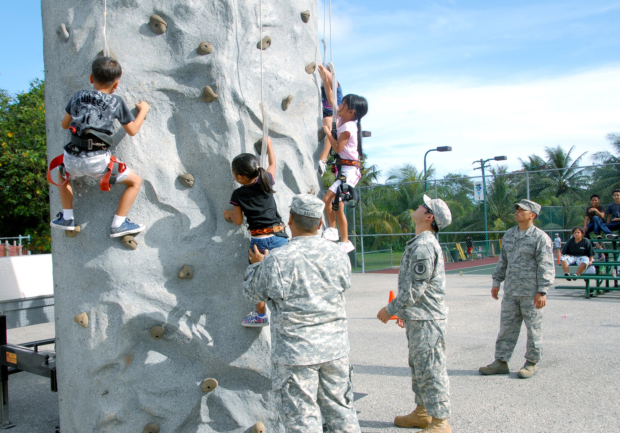 Personnel from the Counterdrug program in Hawaii assist children with the rock wall climbing activity during the Drug Demand Reduction program on Guam, June 29. Counterdrug personnel from Idaho, Hawaii and Guam paid a visit to the Summer Swim Program as part of the DDR mission. The rock wall climbing activity is designed to help build children's confidence and self-esteem as they conquer the rock wall. (U.S. Air Force photo/Tech. Sgt. Betty J. Squatrito-Martin)