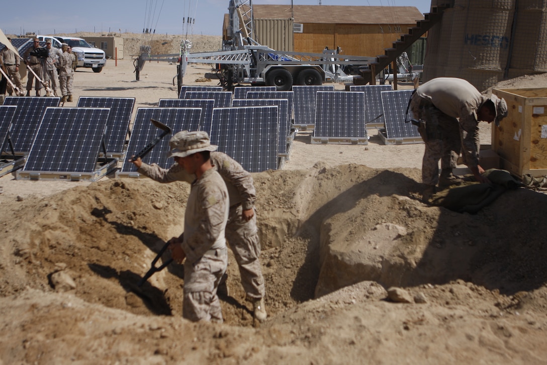 MARINE CORPS AIR GROUND COMBAT CENTER TWENTYNINE PALMS, Calif. – Solar panels soak up rays and convert it to electricity while Marines with 3rd Battalion, 5th Marine Regiment, dig a hole at Combat Center Range 220 July 26. The Marines, based out of Marine Corps Base Camp Pendleton, Calif., are utilizing the panels to power radios, laptop computers, lighting, ventilation and other systems.