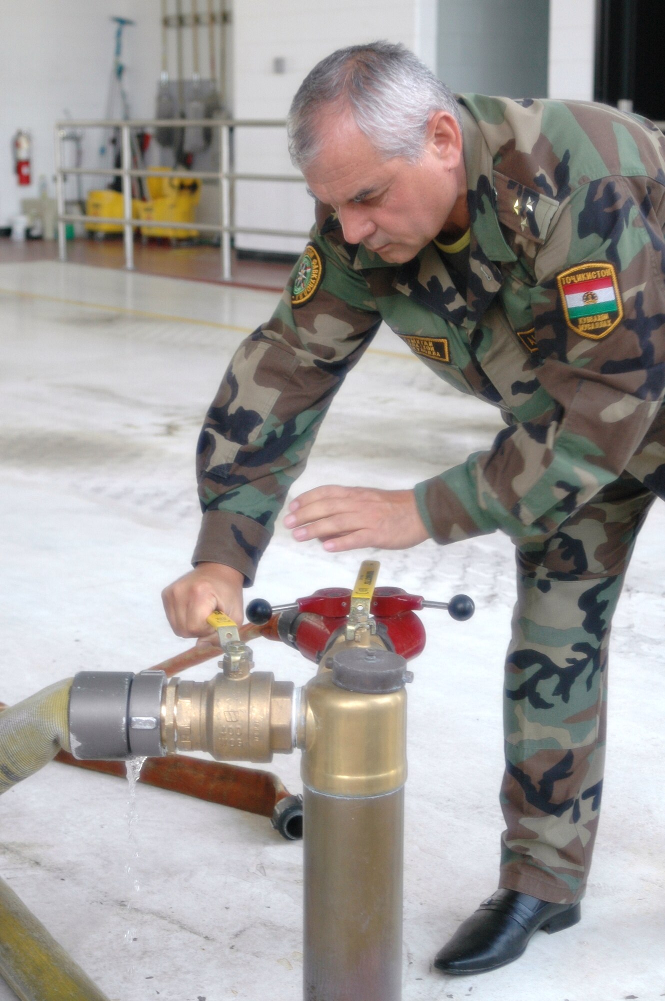 Abdusator Khushuakhtor, head of the Committee on Emergency Situations in Tajikistan, closes off a water line that is used to refill the tank on a crash vehicle.  Photo: Capt. Sherri Pierce 157th ARW-PA