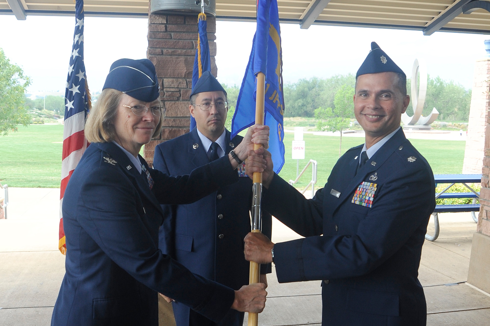 PETERSON AIR FORCE BASE Colo. –Col. Rose Ramirez, commander Personal Property Activity Headquarters, San Antonio, Texas, passes the flag of the Joint Personal Property Shipping Office to Lt. Col. Paul M. Zuluaga, commander JPPSO-Colorado Springs.  The ceremony took place July 21 at America the Beautiful Park. (U.S. Air Force photo/Dennis Howk)