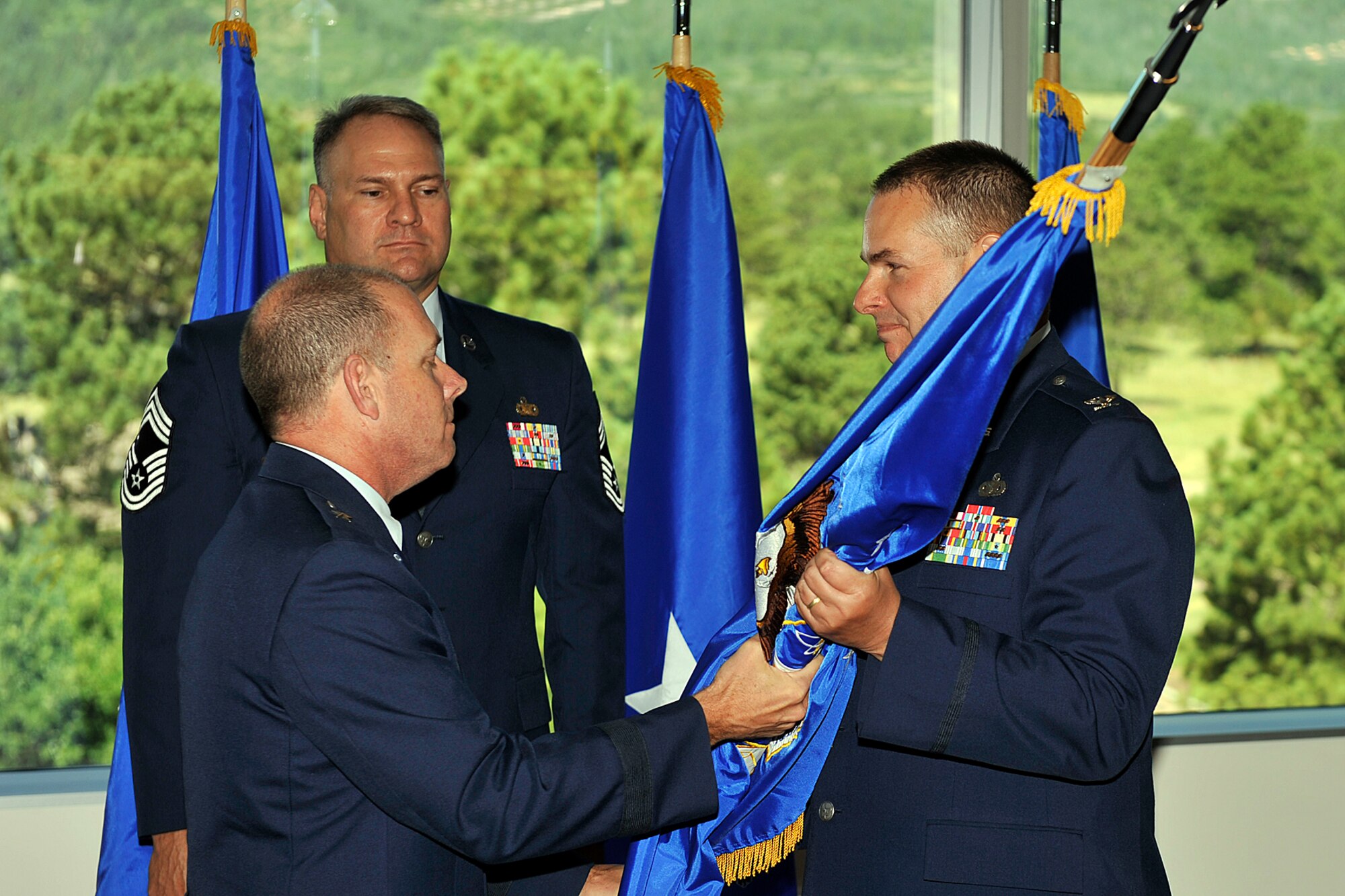 U.S. AIR FORCE ACADEMY, Colo. – Brig. Gen. Kevin Jacobsen, Air Force Office of Special Investigations commander from Andrews Air Force Base, Md., (left) hands over the OSI Region 8 squadron flag to Col. Eddie Howard, who took command of the 8th Field Investigations office on Peterson Air Force Base July 16 during a ceremony held at the U.S. Air Force Academy. OSI is a field operating agency of the Air Force and provides investigative services to commanders. (U.S. Air Force photo/Larry Hulst)