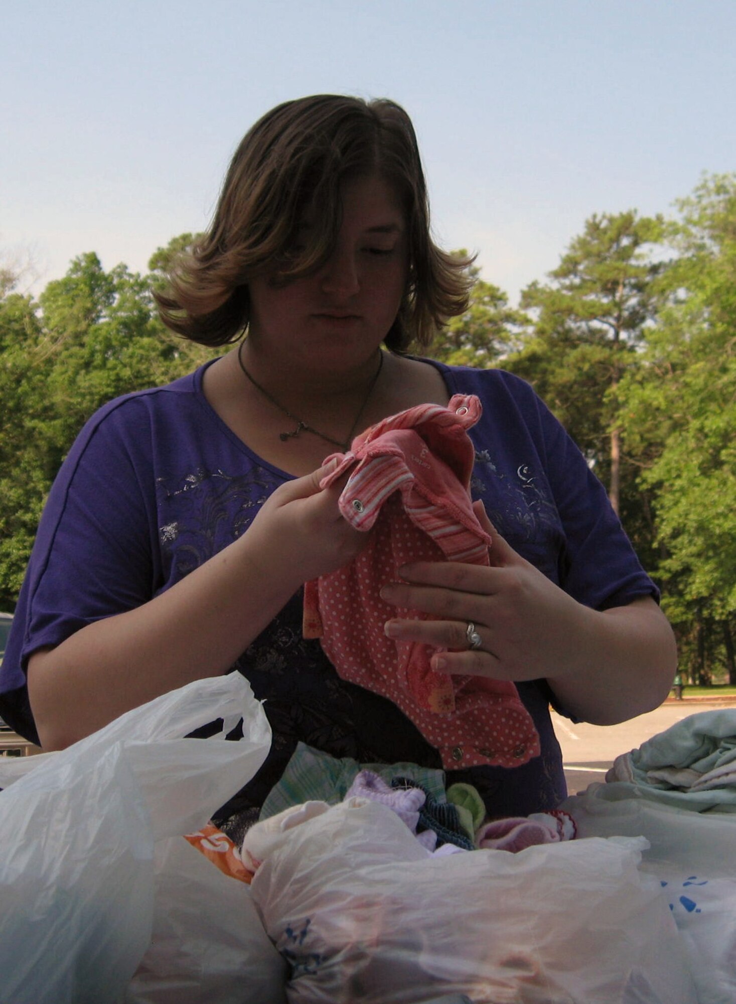 SEYMOUR JOHNSON AIR FORCE BASE, N.C. – Erica Johnson browses through a stack of baby clothes at a multi-family yard sale in the Heritage Hall parking lot here July 24, 2010. Erica is the wife of Airman 1st Class Nate Johnson, 333rd Aircraft Maintenance Unit avionics system technician. (U.S. Air Force photo/Tech. Sgt. Tammie Moore)