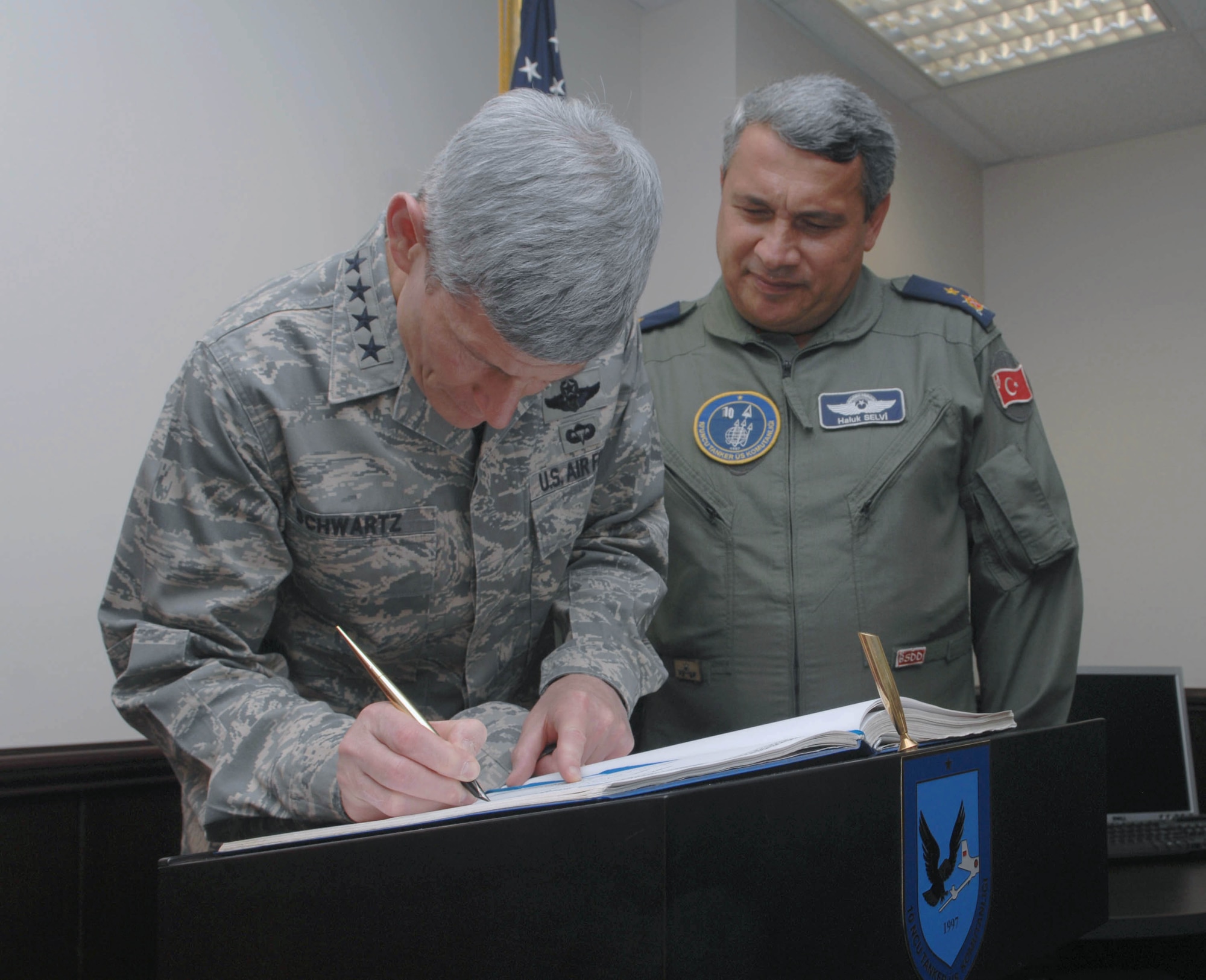 Turkish air force Brig. Gen. Haluk Selvi observes as Air Force Chief of Staff Gen. Norton Schwartz signs the honor book for the 10th Tanker Base Command July 21, 2010, at Incirlik Air Base, Turkey. Signing the book is a 10th Tanker Base command tradition when distinguished visitors arrive here. General Selvi is the 10th Tanker Base commander. (U.S. Air Force photo/Tech. Sgt. Valda G. Wilson)